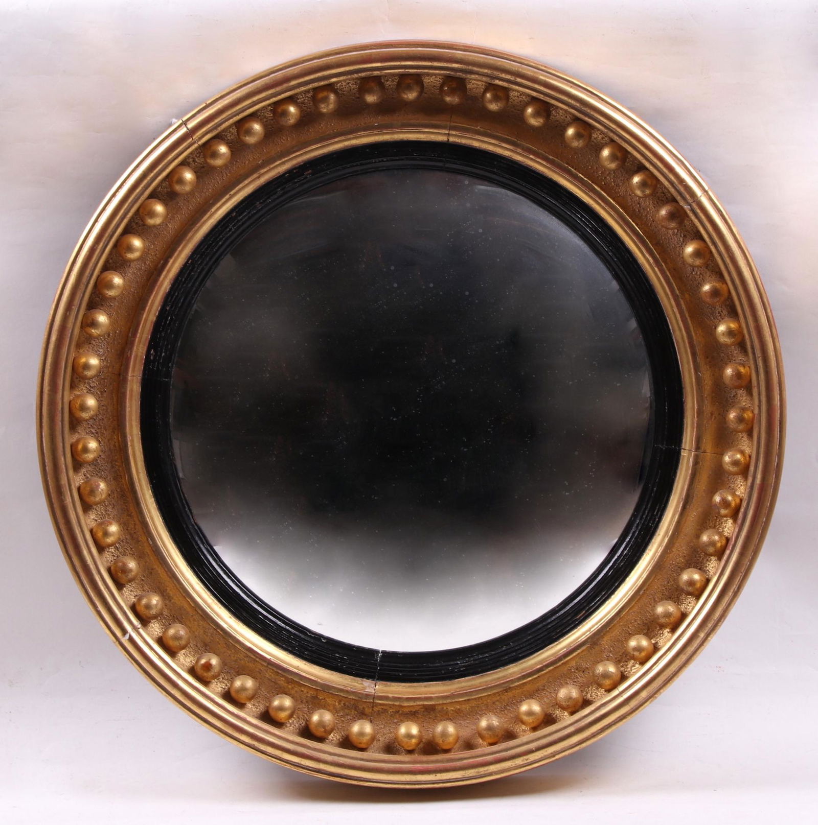 A Convex Federal Style Gilt Mirror: 20th century, circular with a molded frame and applied ball decoration. Dimensions: 26 1/2" in diameter, 3 1/2" deep. Provenance: From a Philadelphia collection.
