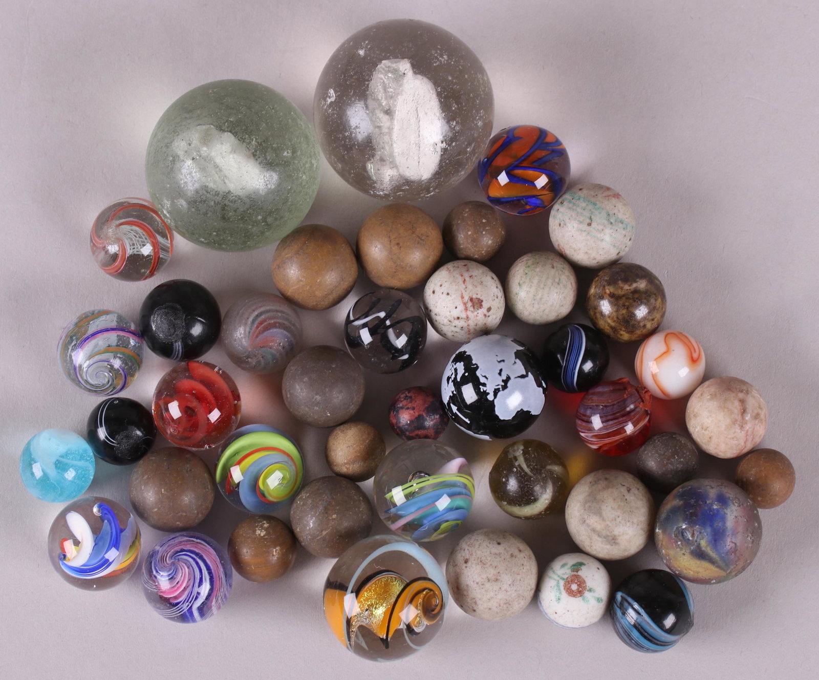 A Group of Vintage Toy Marbles: Forty two examples, various sizes and materials including clay, glass and sulfide. Dimensions: From 3/8" to 1 1/2" in diameter.