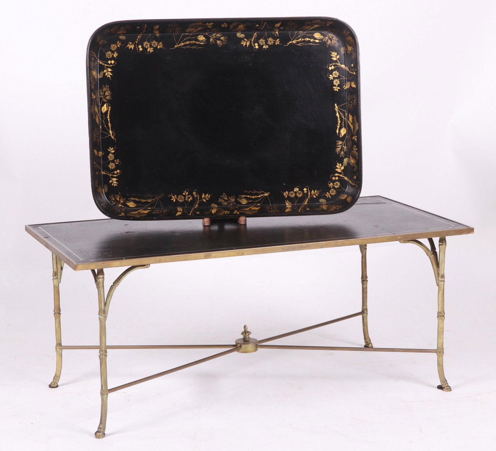 Estate Lot, A Coffee Table and Tray: A 20th century coffee table with a brass base that features hoof feet below an ebonized wooden top and a Victorian period papier mache tray with gilt decoration. Dimensions: The table is 20" x 40" and