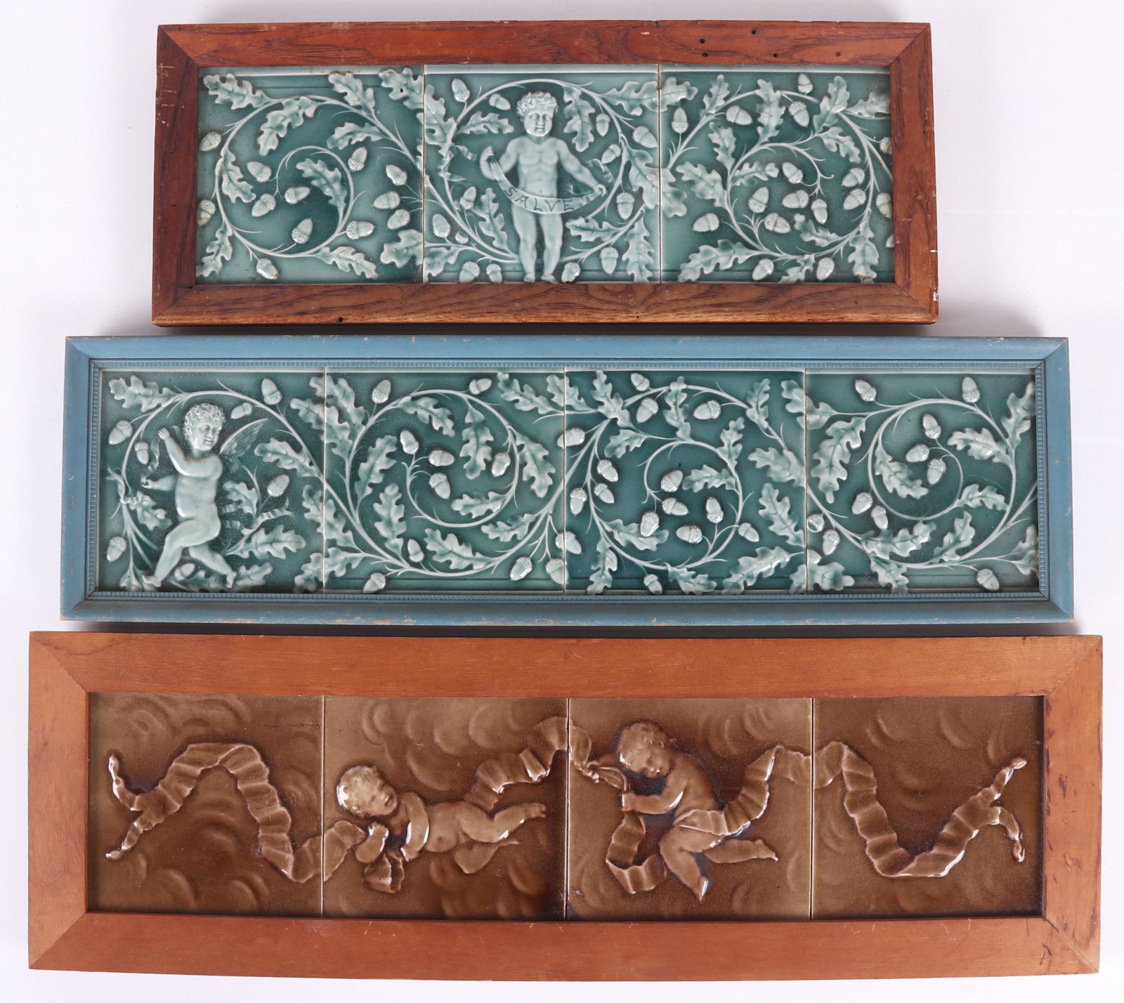 Three Framed Art Pottery Tile Panels: All 19th century, each decorated with putti. Dimensions: The frames range from 7 3/4" x 19 1/2" to 8 1/2" x 26 3/4".