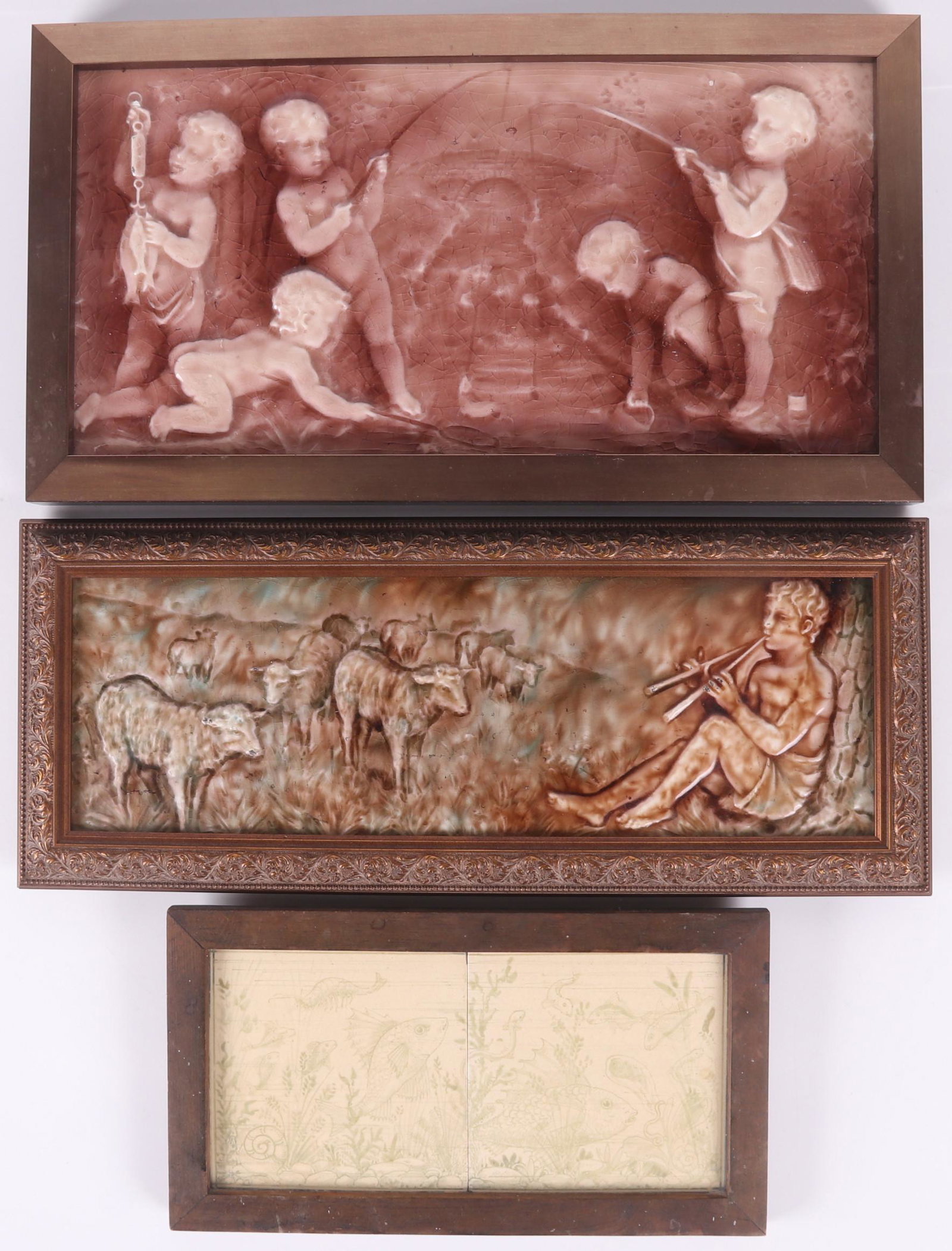 Three 19th Century Art Pottery Tiles, Framed: A large tile depicting putti fishing, a similar smaller example depicting a shepherd with sheep and a panel of two tiles depicting sea life. Dimensions: The frames measure 7 1/2" x 13 1/2" and 10 3/4"