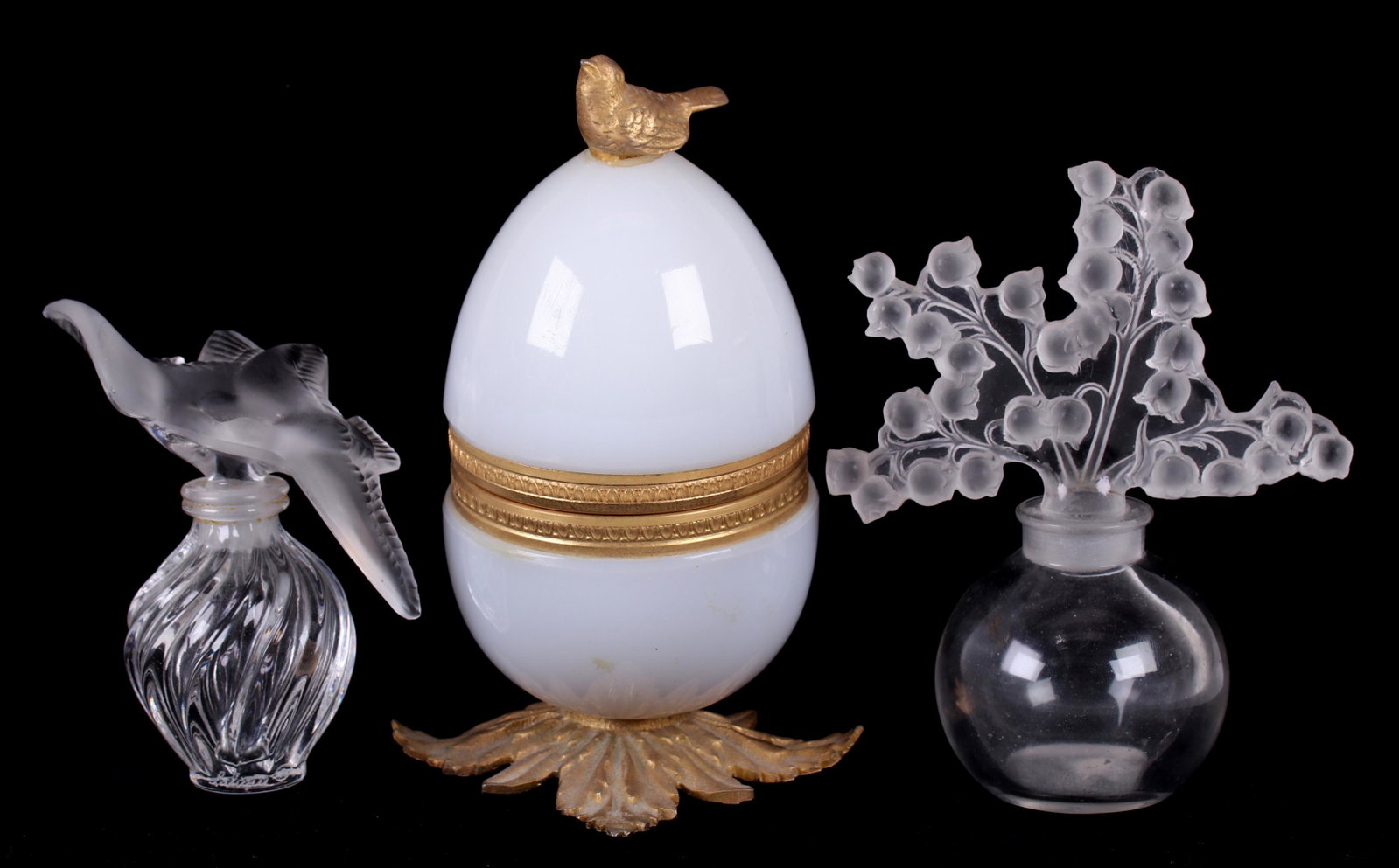 Three Perfume Bottles, Including Lalique: Lalique "Clairefontaine" bottle and "Nina Ricci" each with an acid etched mark as pictured and a Neiman Marcus ormolu mounted glass egg with bottle at the interior. Dimensions: From 3 1/2" x 2" to 4" 