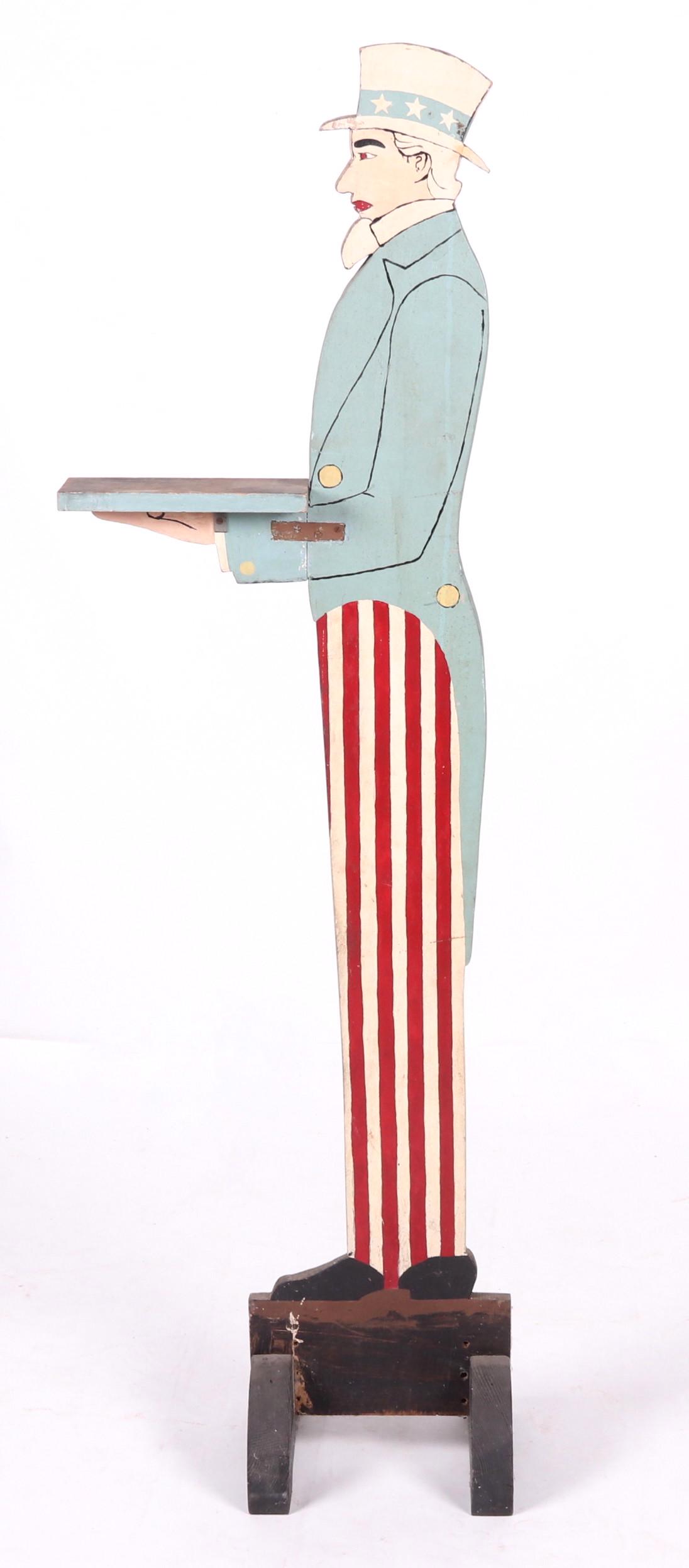 A Large Vintage Wooden Uncle Sam Figure: Appears to be mid 20th century, with platform made for holding items. Dimensions: 11 1/2" x 10", 61 1/2" tall.