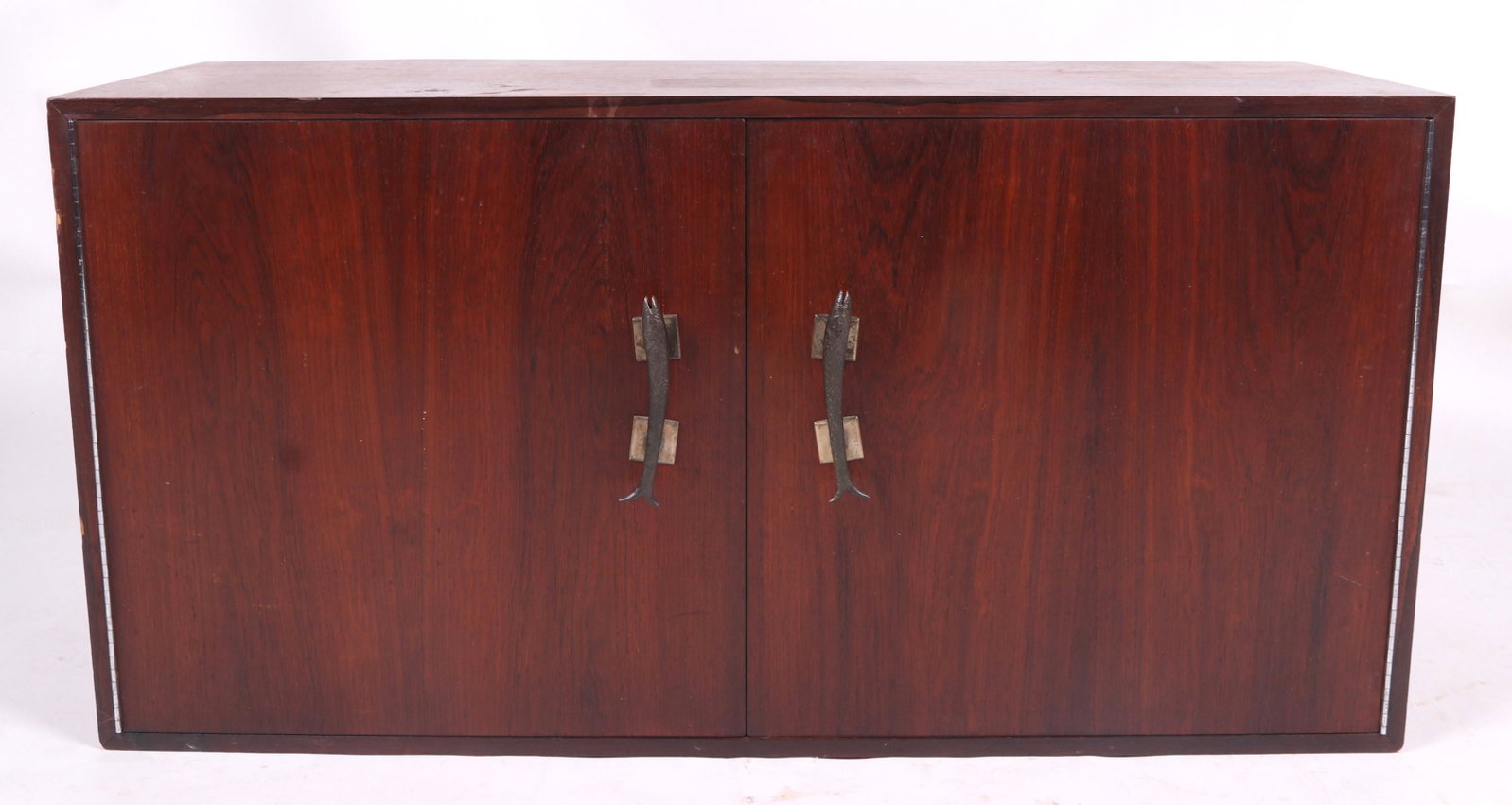 Mid Century Rosewood Floating Cabinet: A wall mounted cabinet with rosewood veneer and cast metal fish form handles. Dimensions: 18" x 48", 24" tall. Provenance: From a Philadelphia collection.