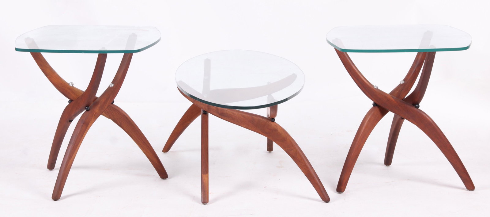 Three Folding Teak and Glass Modernist Tables: A pair of lamp stands and a matching coffee table, unsigned. Dimensions: The lamp stands at 27" x 20" and 21" tall, the coffee table is 53" x 19" and 15" tall.