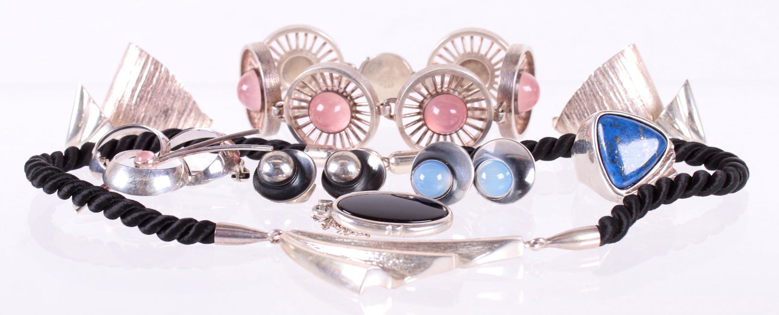 Danish Modern Sterling Jewelry by N.E. From: All marked for sterling and the maker, comprising: a pair of earrings set with blue chalcedony, a pendant set with black onyx, a bracelet with circular links, each set with a small rose quartz stone,