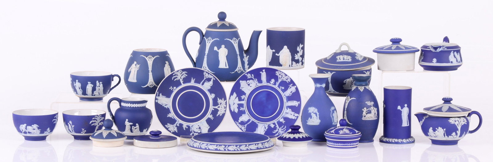 A Group of Wedgwood Blue Jasperware: Late 19th and 20th centuries, comprising: a trivet, a handleless cup, a small bottle form vase, a creamer, a teapot with matching open sugar, another open sugar bowl, a cylindrical bud vase, another b