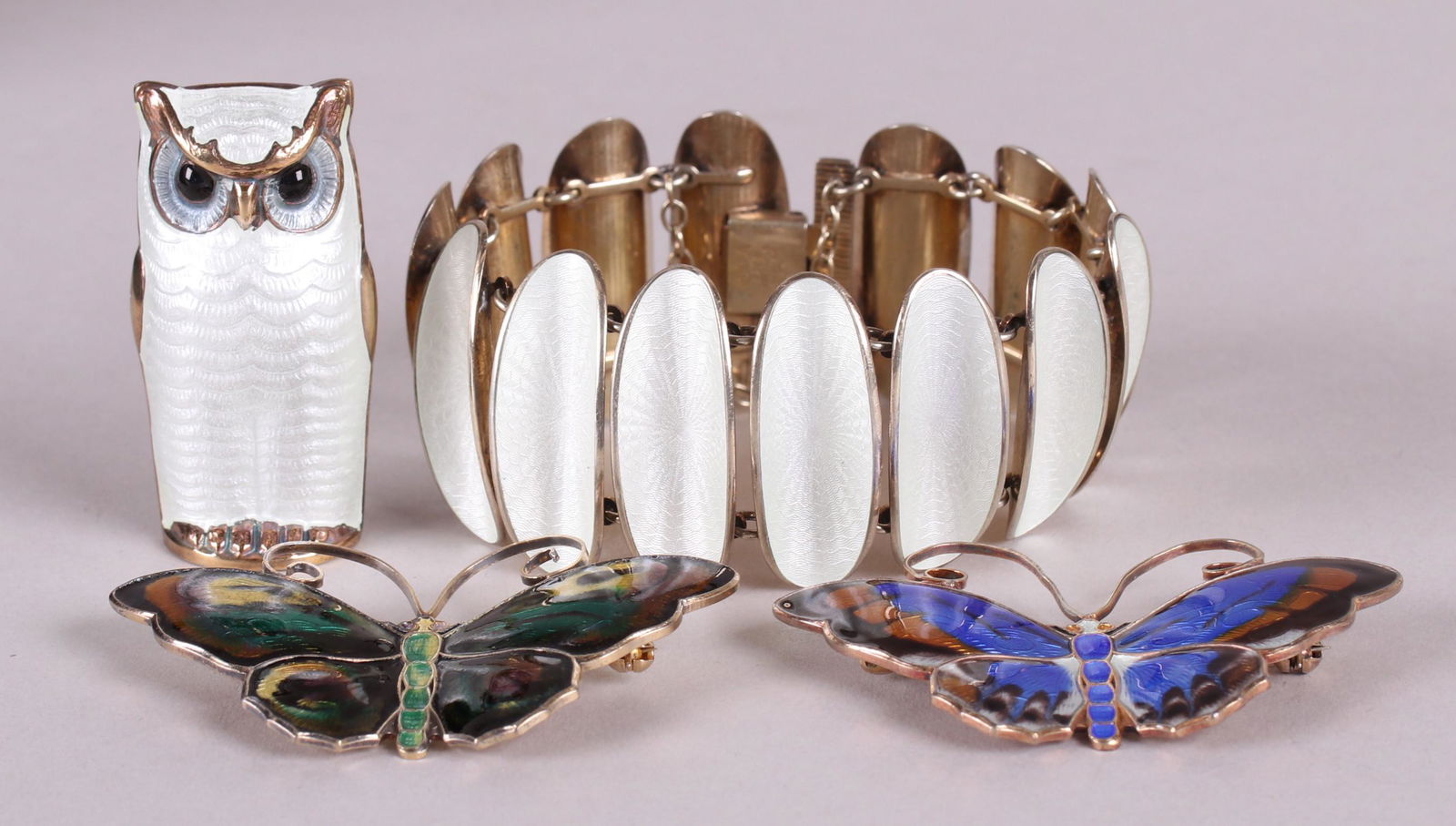 David Andersen, Norway Sterling & Enamel Jewelry: A large white owl brooch, a bracelet with white oblong links, and two multicolored butterfly pins. All marked for the maker and for sterling. Dimensions:From 1 1/2" x 2 1/4" to 7" x 1 1/4". The total