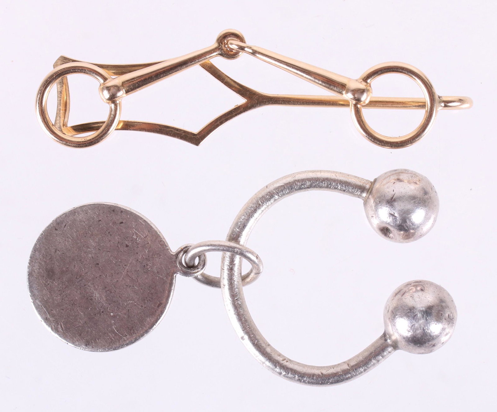 Two Tiffany & Co. Items, Sterling and 14k Gold: A 14k gold tie bar and a sterling silver arched key ring, both marked as pictured. Dimensions:The tie bar is 2" x 1/2" and weighs approximately 3.5 dwt, the key ring is 1" x 1" and weighs approximatel
