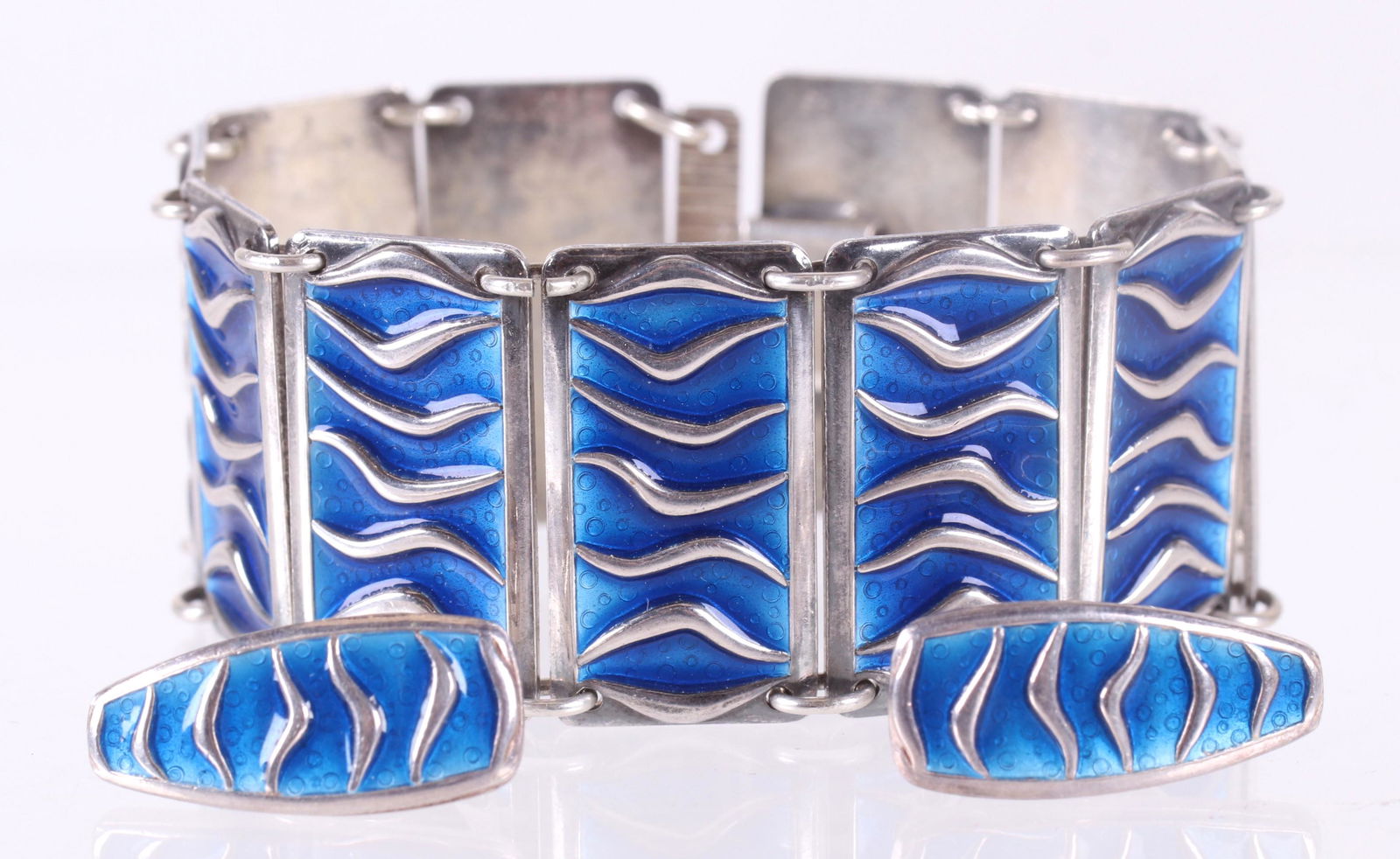A Sterling Enamel Set, David Andersen: A three piece modernist sterling and enamel set, a bracelet and pair of matching earrings, all with blue enamel. Dimensions:Each earring is 1" x 1/4", the bracelet is 6 3/4" x 1". The total approximat