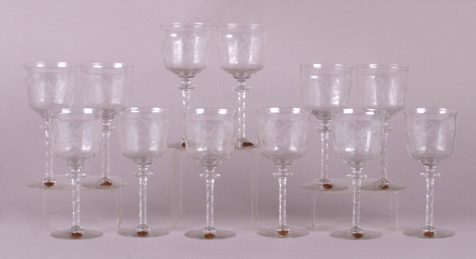 A Set of Twelve Tiffin Crystal Wine Glasses: In the "Cadena Clear" pattern, each with a circular foot, branch form stem, disc knop and a bowl with optic ribbing and etched foliate decoration. Labeled as pictured. Dimensions: Each is 3 1/2" in di