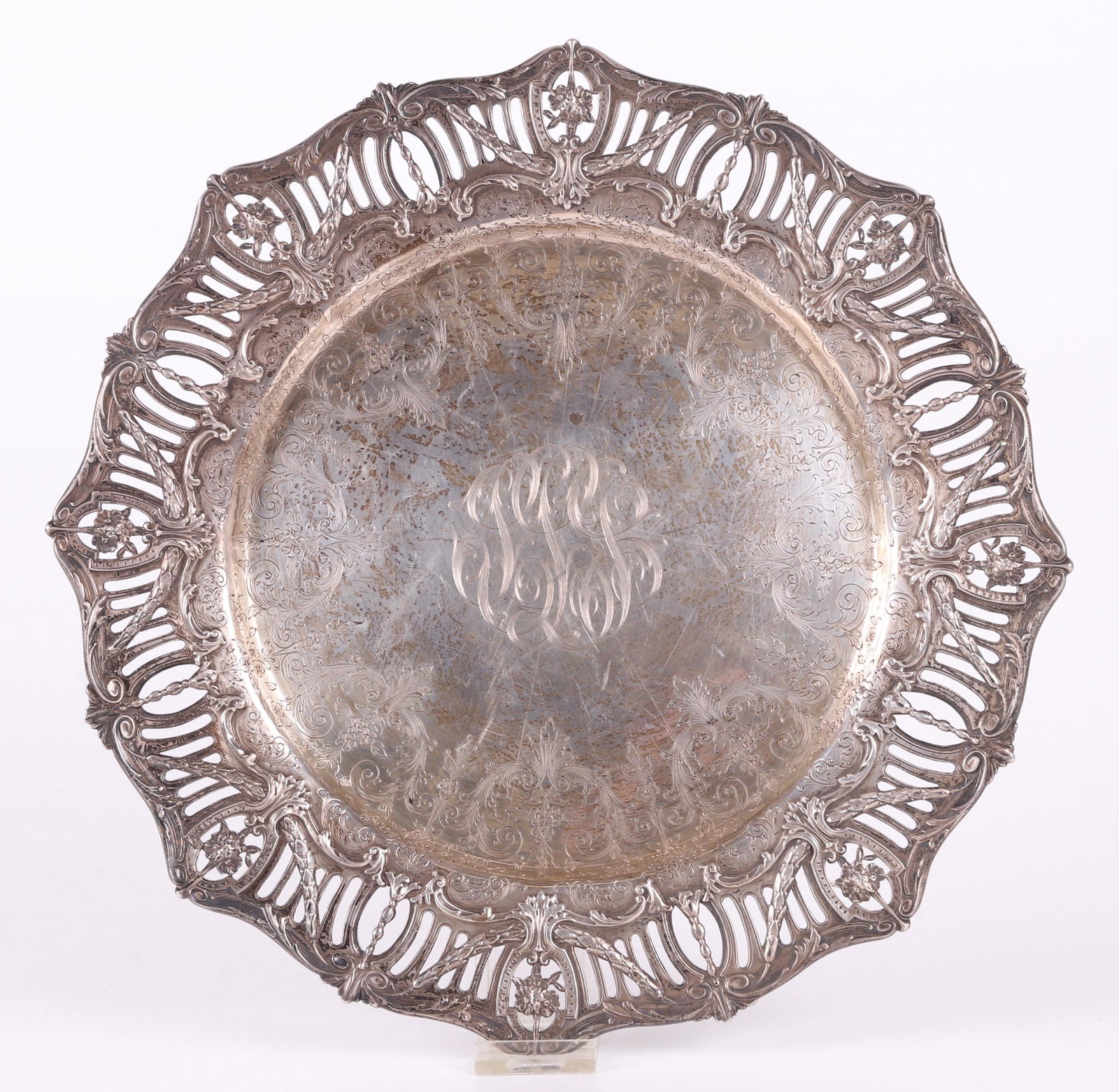 A Sterling Charger by Graff, Washbourne & Dunn: Early 20th century, made for Bailey, Banks and Biddle, Philadelphia. With a neoclassical reticulated edge and engraved foliate and floral decoration. Dimensions: 13 1/2" in diameter, the approximate w