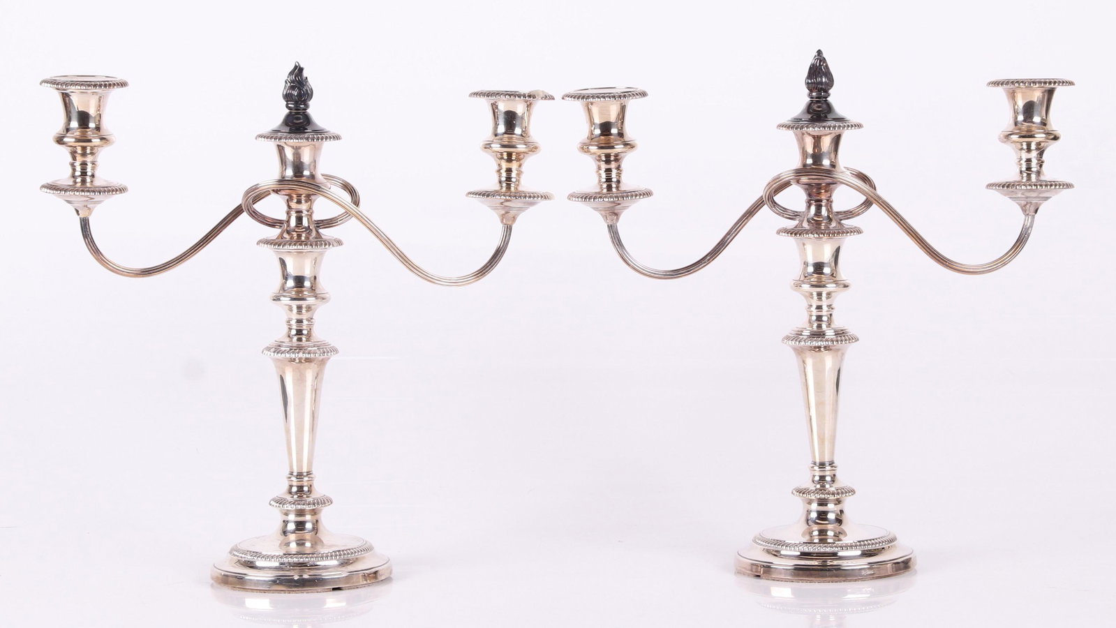 A Pair of English Silver Plated Candelabra: Early 20th century, marked for Ellis Barker Silver Co.Each with three lights, gadrooning and central flame finial. Dimensions: Each is 13 1/2" x 5", the height is 14 1/2". Provenance: From a local col