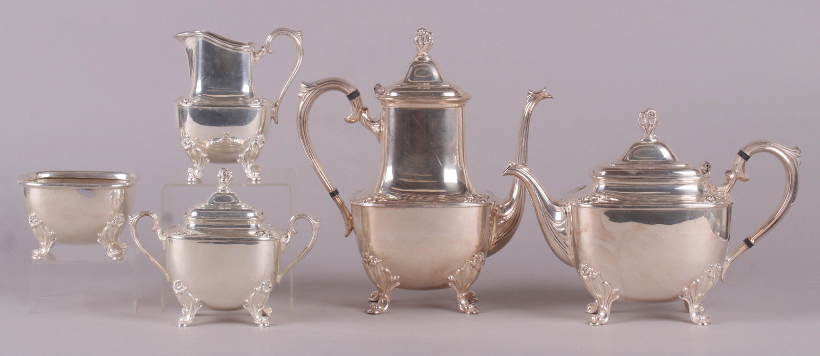 A Silver Plated Tea Service by Rogers: In the "Daffodil" pattern. A coffeepot, teapot, creamer, sugar, and waste bowl. Dimensions: From 4 1/2" x 4 1/4" to 11" x 5", the heights range from 3" to 11 1/2".