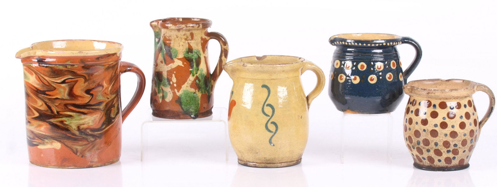 Five Jaspe Pottery Pitchers: With polka dot, marbled an floral decoration, all unsigned. Dimensions: From 6" x 4" to 8" x 6", the heights range from 4 1/2" to 7". Provenance: From a local collection.