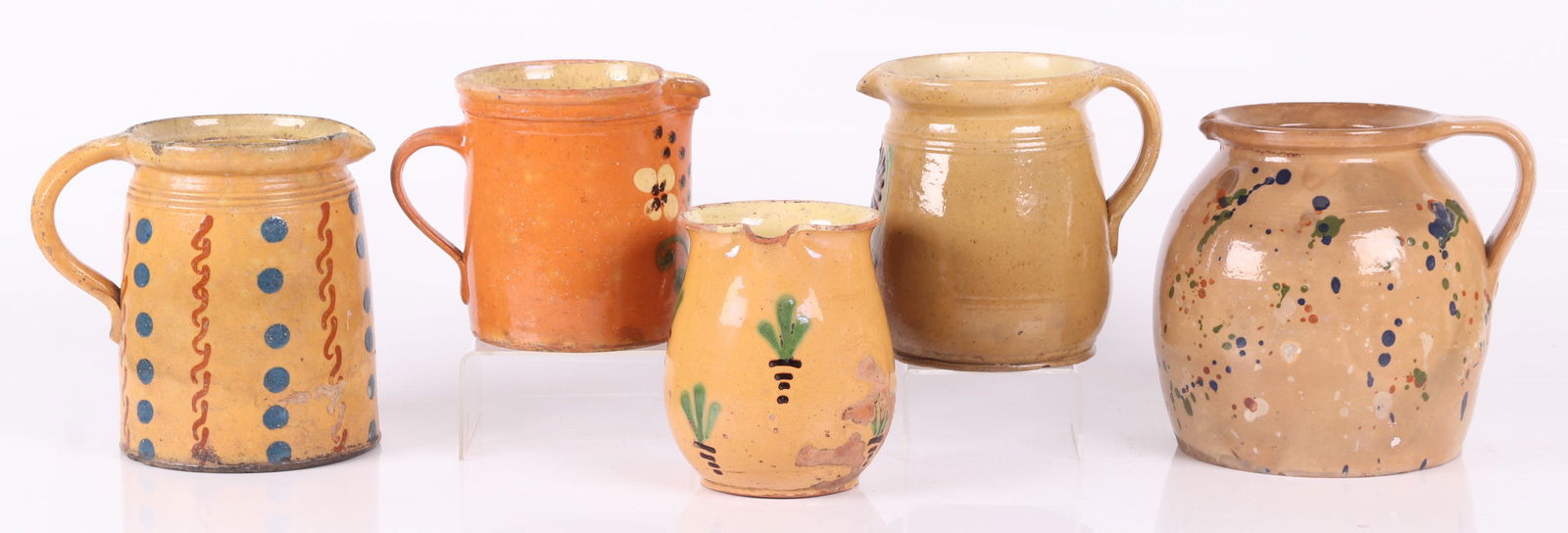 Five Large Redware Pitchers: Continental, including Jaspe, with various decoration including polka dots, flowers and splashes of color. Dimensions: From 6" x 4 1/2" to 8" x 7", the heights range from 6" to 8". Provenance: From a