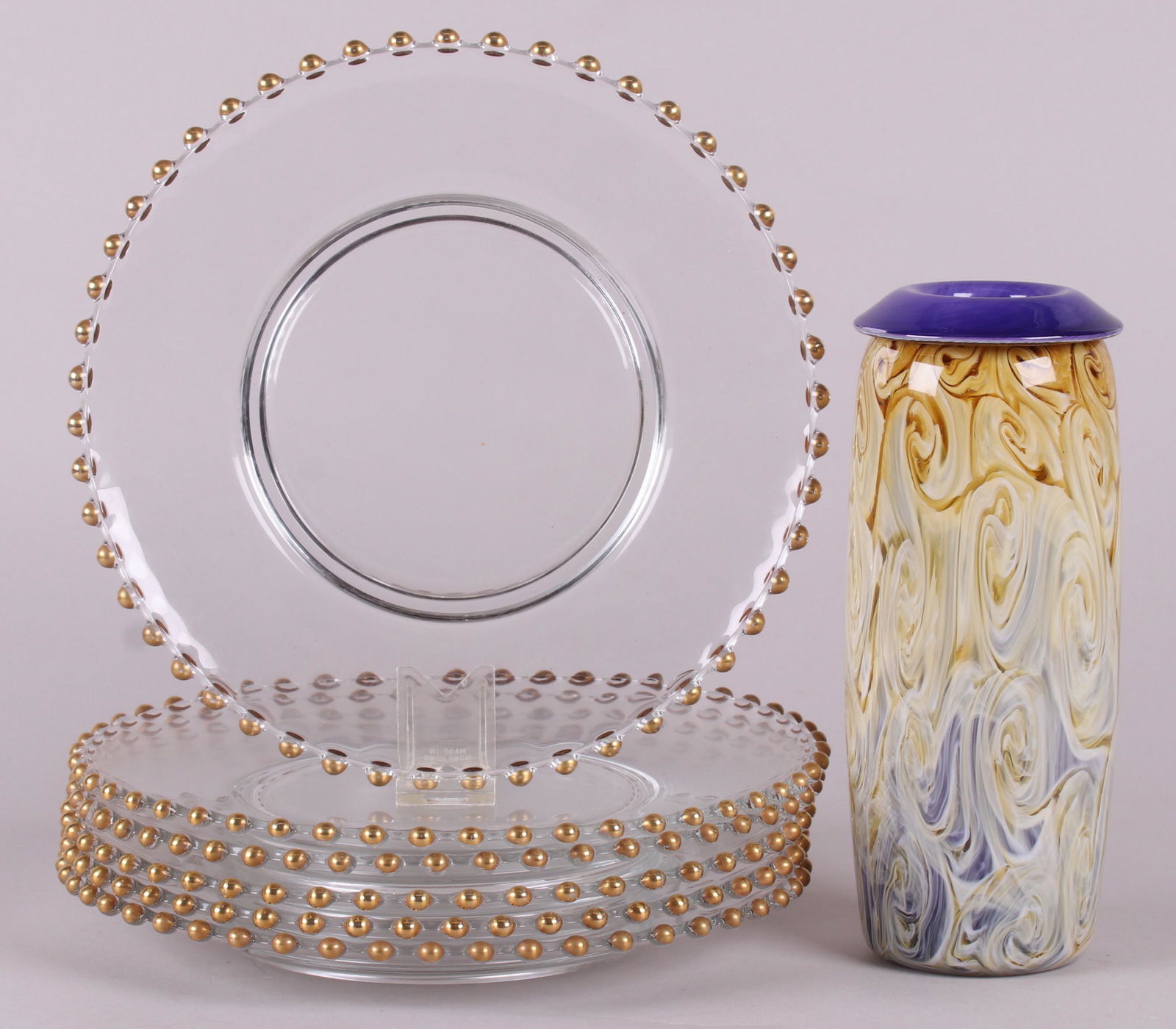 A Group of Glass Including Henry Levine: A circa 1990 art glass vase signed for Henry Levine and a set of six large glass vintage dinner plates with gold ball decoration at the rims signed for Dalzell. Dimensions: The vase has a diameter of