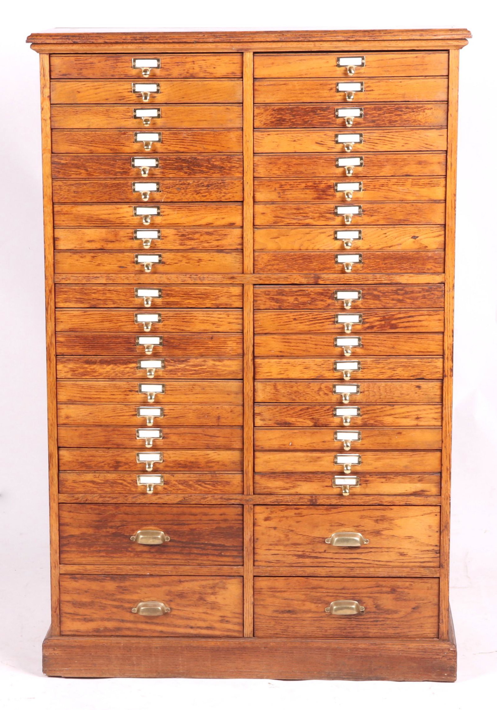 An Oak Printer's Cabinet: Circa 1900, with forty drawers, paneled sides and molded base and cornice. Dimensions: 38" x 17", 58 1/2" tall. Provenance: From a local collection.
