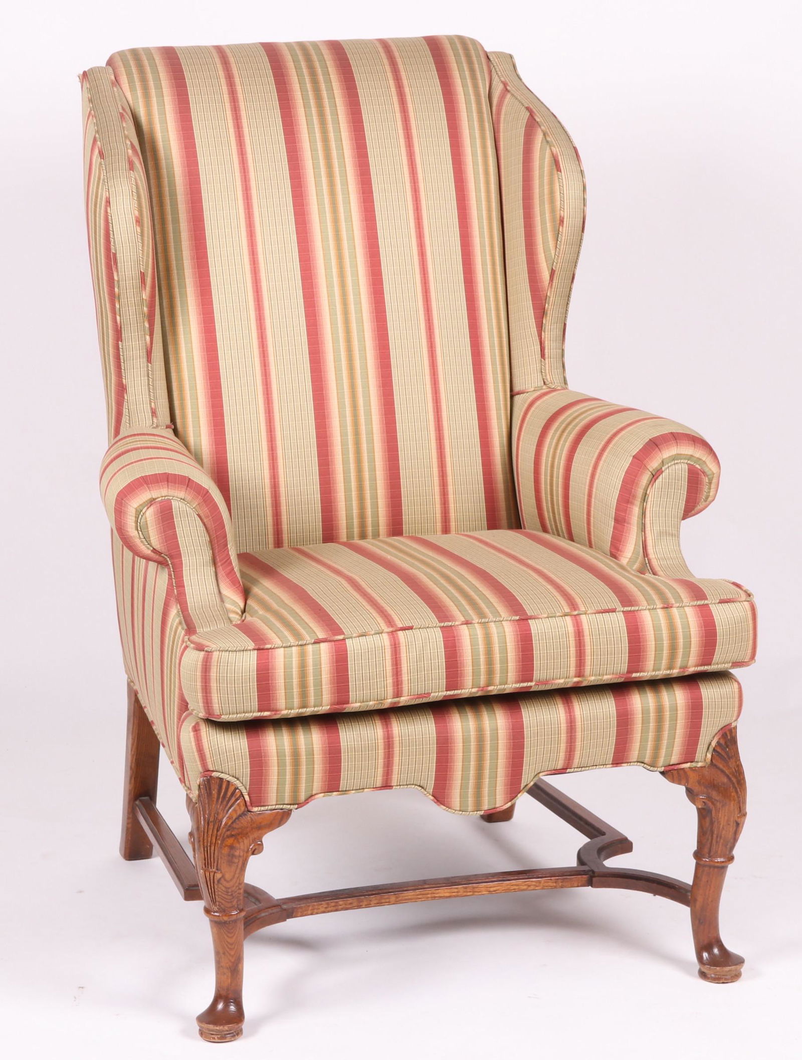 A Queen Anne Style Wingback Chair: Oak, with pad feet, cabriole legs, shell carved knees, and scrolled arms, unmarked. Dimensions: 32" wide, 29" deep, seat height is 20", overall height 45 1/2" Provenance: From a local collection.