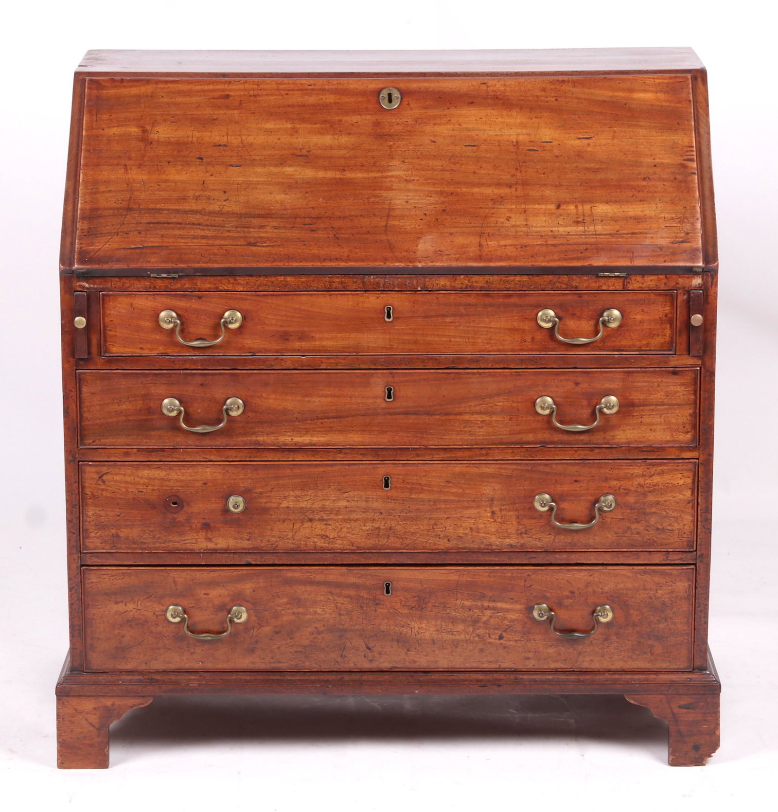 George III Mahogany Slant Front Desk: Circa 1800, the straight bracket feet below four graduated, cockbeaded and dovetailed drawers, a writing surface that opens to reveal an interior with six small drawers below eight cubby holes. Retain
