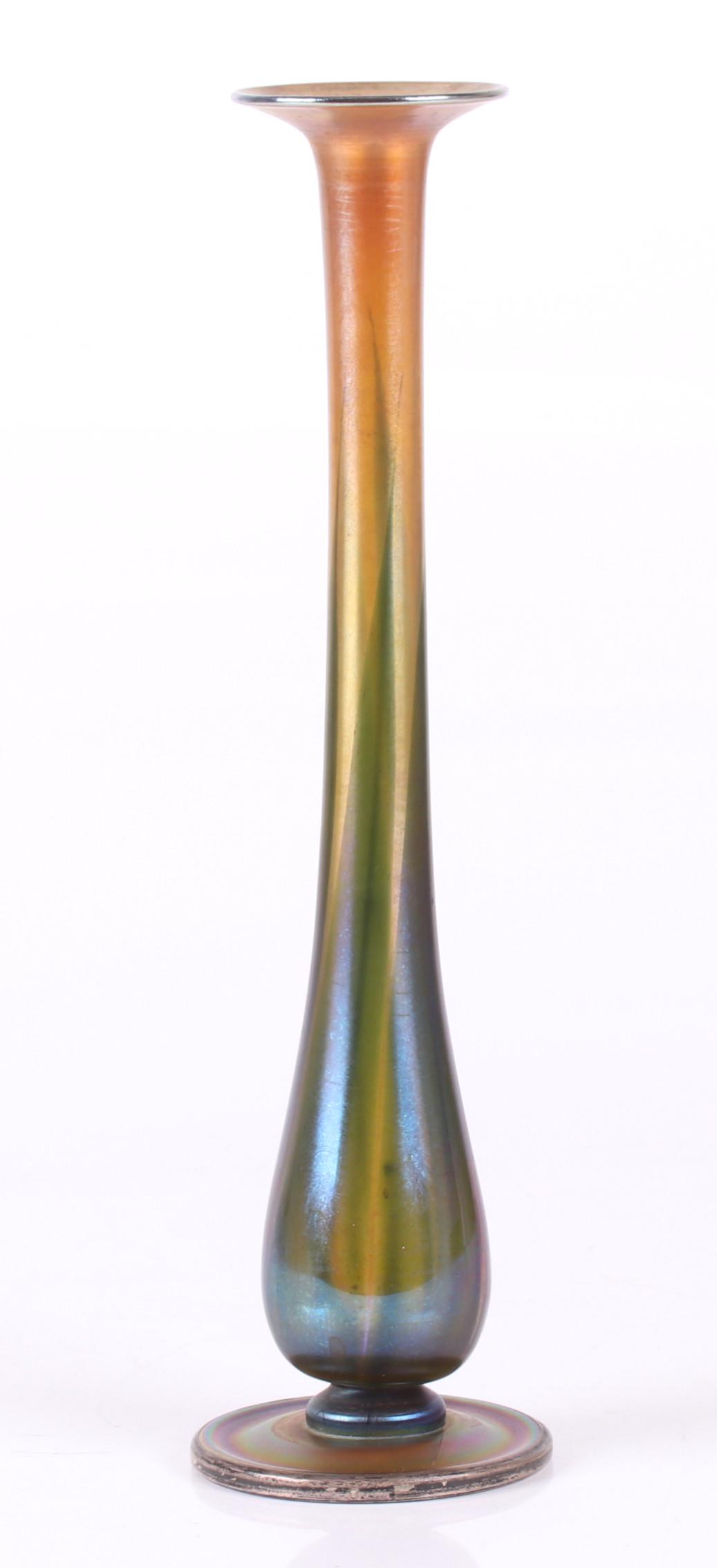 A Tiffany Favrile Glass Vase: With a circular foot, elongated body and flared top edge. With a sterling make-do repair at the foot. The marking is barely visible from the top. Dimensions: The foot is 3 1/2" in diameter, the height