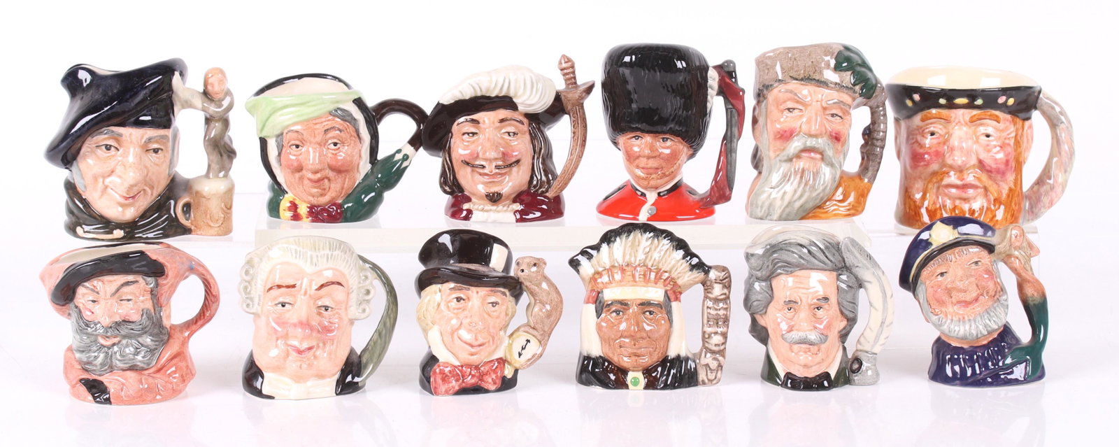 Twelve miniature Royal Doulton character mugs: The Guardsman, The Lawyer, Robinson Crusoe, North American Indian, Tam O'Shanter, Mad Hatter, Old Salt, Sairey Gamp, Mark Twain, Falstaff, Porthos, and Henry VIII (not Royal Doulton). Dimensions: From