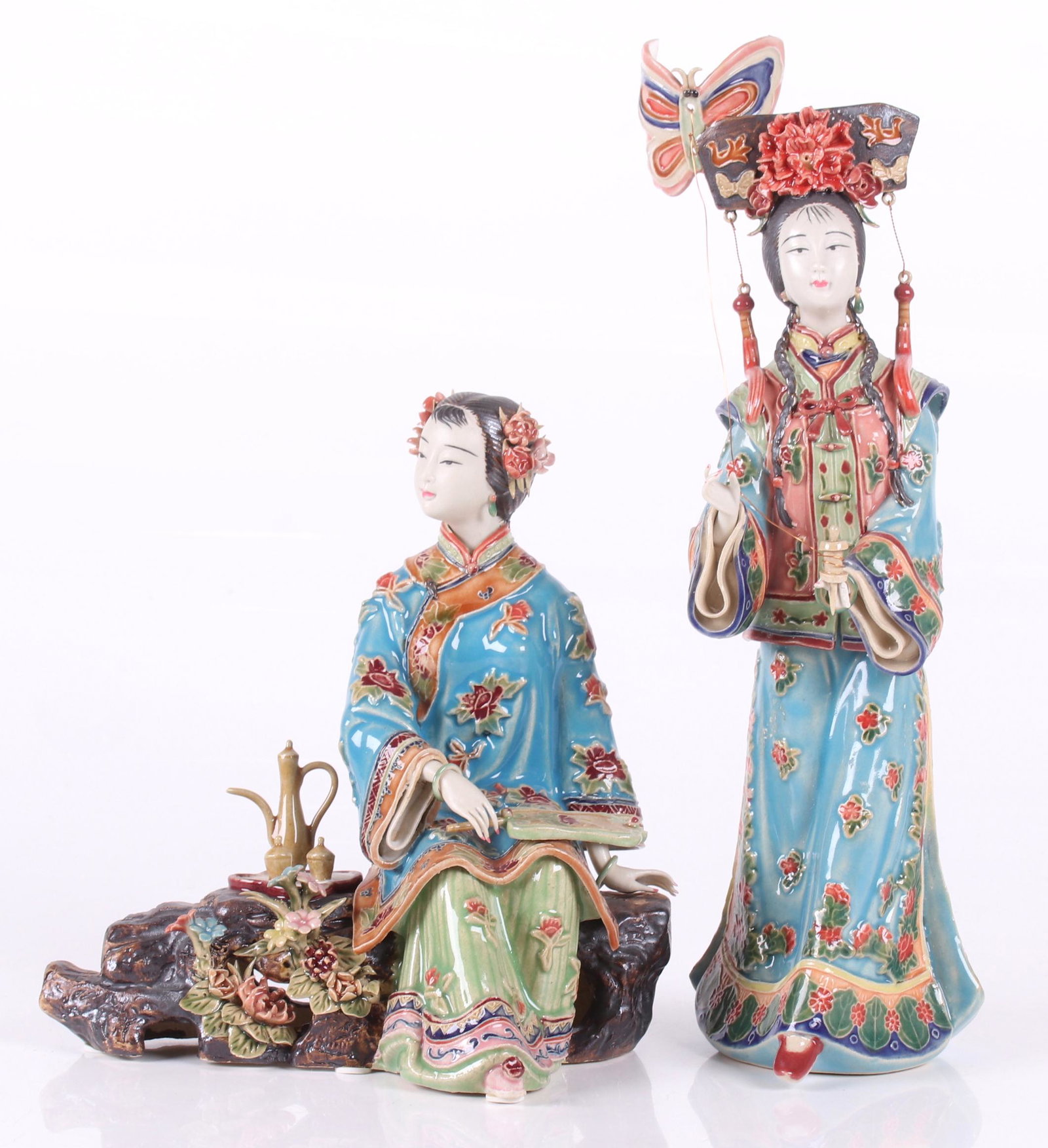 A Pair of Chinese Shiwan Pottery Figures: 20th century/modern, each depicting a young woman dressed in traditional garb. Each artist signed. Dimensions:The standing figure is 5" x 4" and 13 1/2" tall, the seated figure is 9" x 5" and 9" tall.