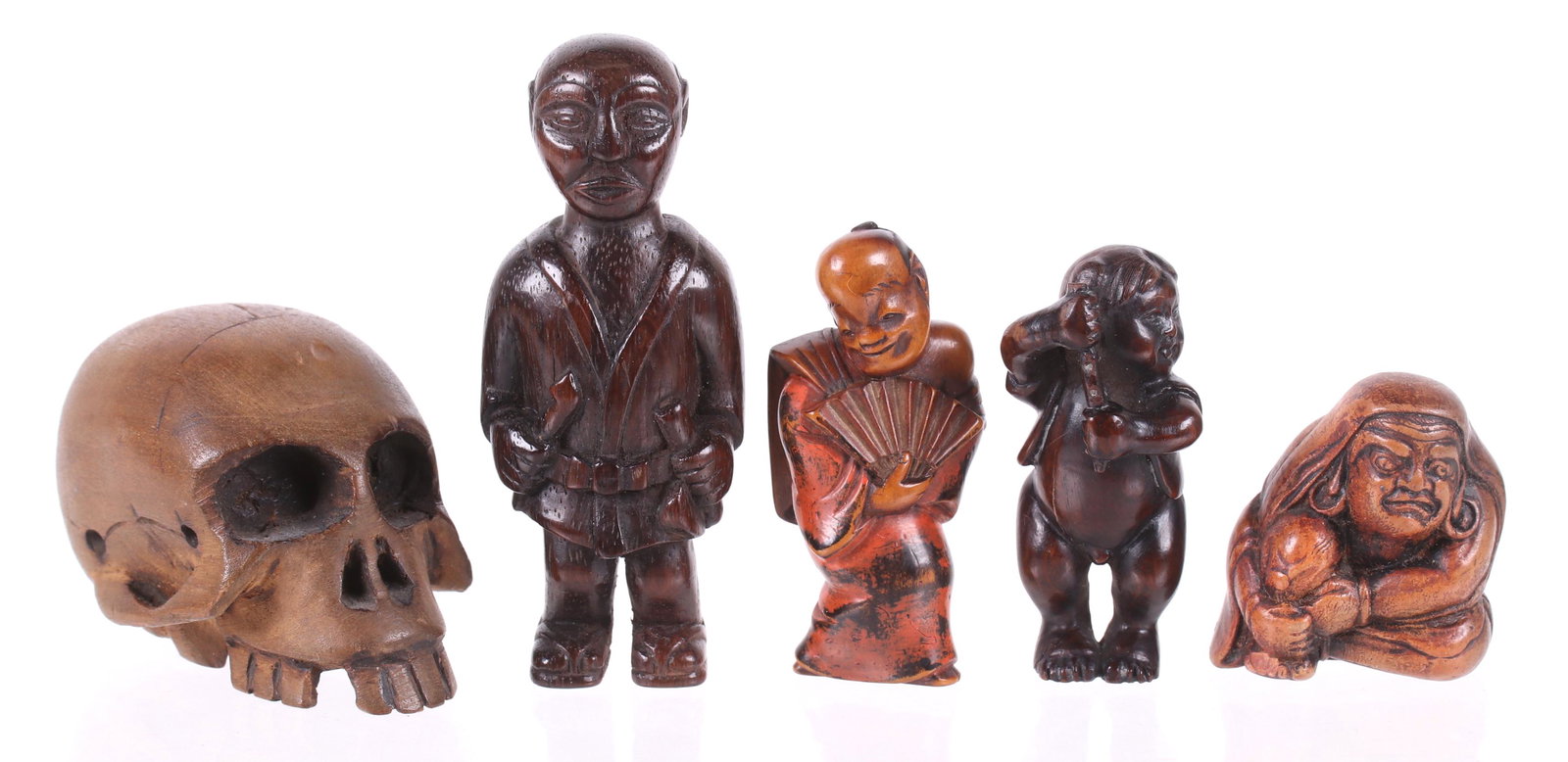 Five Wooden Netsuke, Figures: In the form of a boy holding an implement, a standing man, a man holding a fan with polychrome, a seated Daruma, and a large skull. Dimensions: From 3/4" x 3/4" to 2 1/2" x 1 1/2", the heights range f