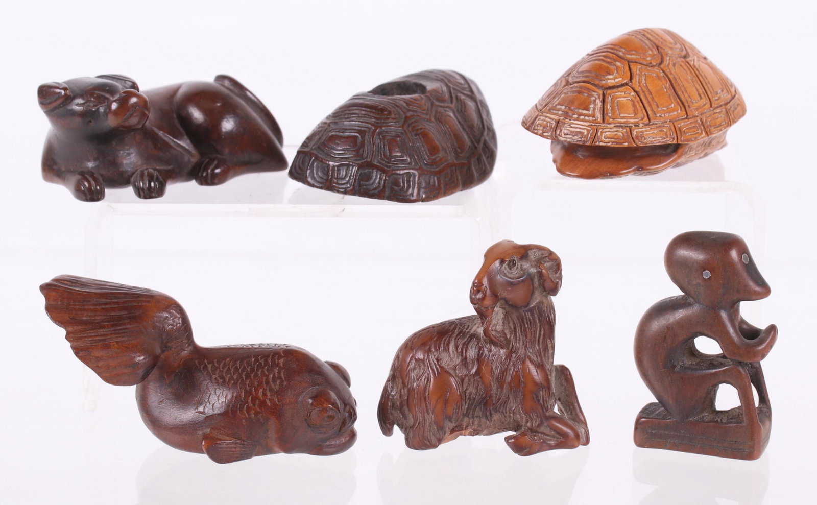 A Group of Wooden Netsuke, Animals: Comprising: two turtle shells, a ram, a reclining dog, a seated monkey with inlaid metal eyes, and a koi. Dimensions: From 1/4" x 1" to 2 1/4" x 1 1/2", the heights range from 1" to 1 3/4". Provenance