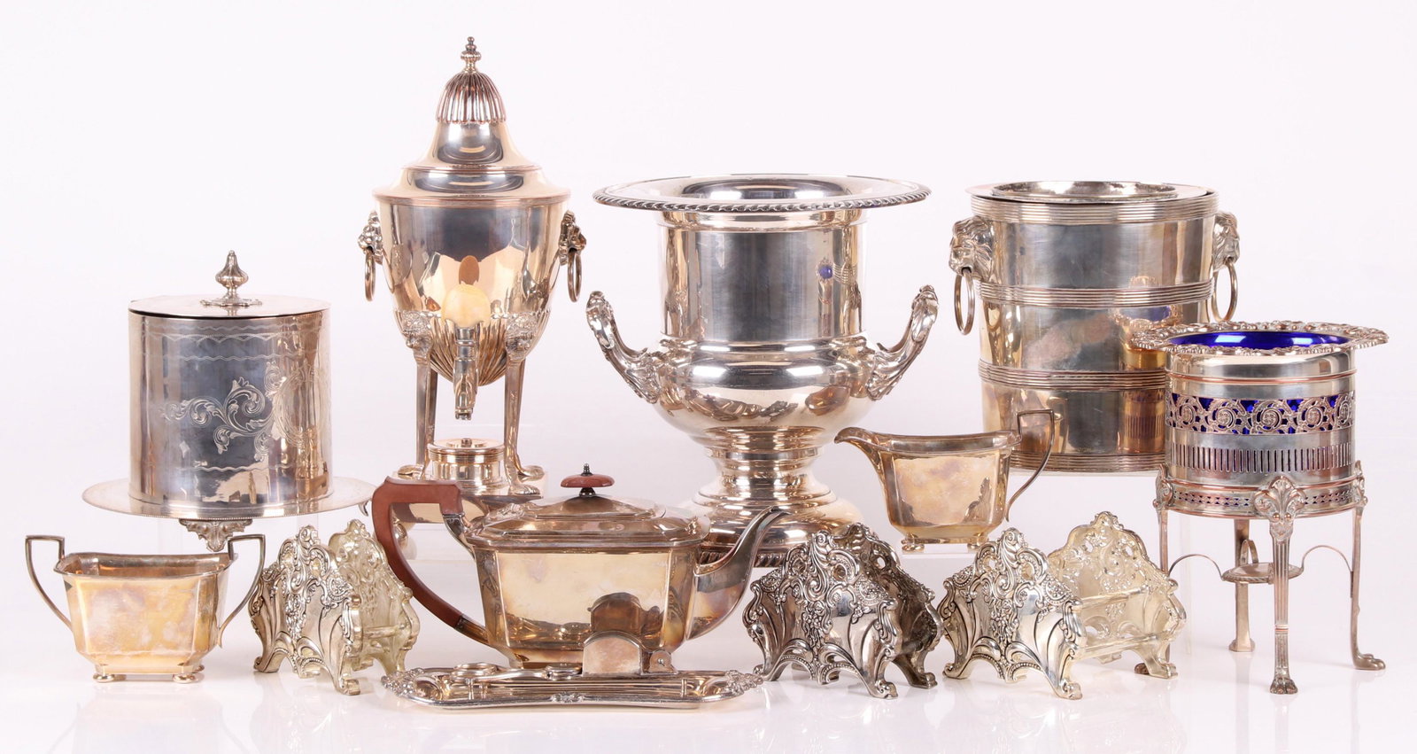 A Group of English Silver Plated Tableware: An Old Sheffield Plate barrel form wine cooler with lion mask ring handles, a Harrison Brothers and Howson three piece tea set, a Victorian biscuit jar with attached stand and engraved decoration, a s