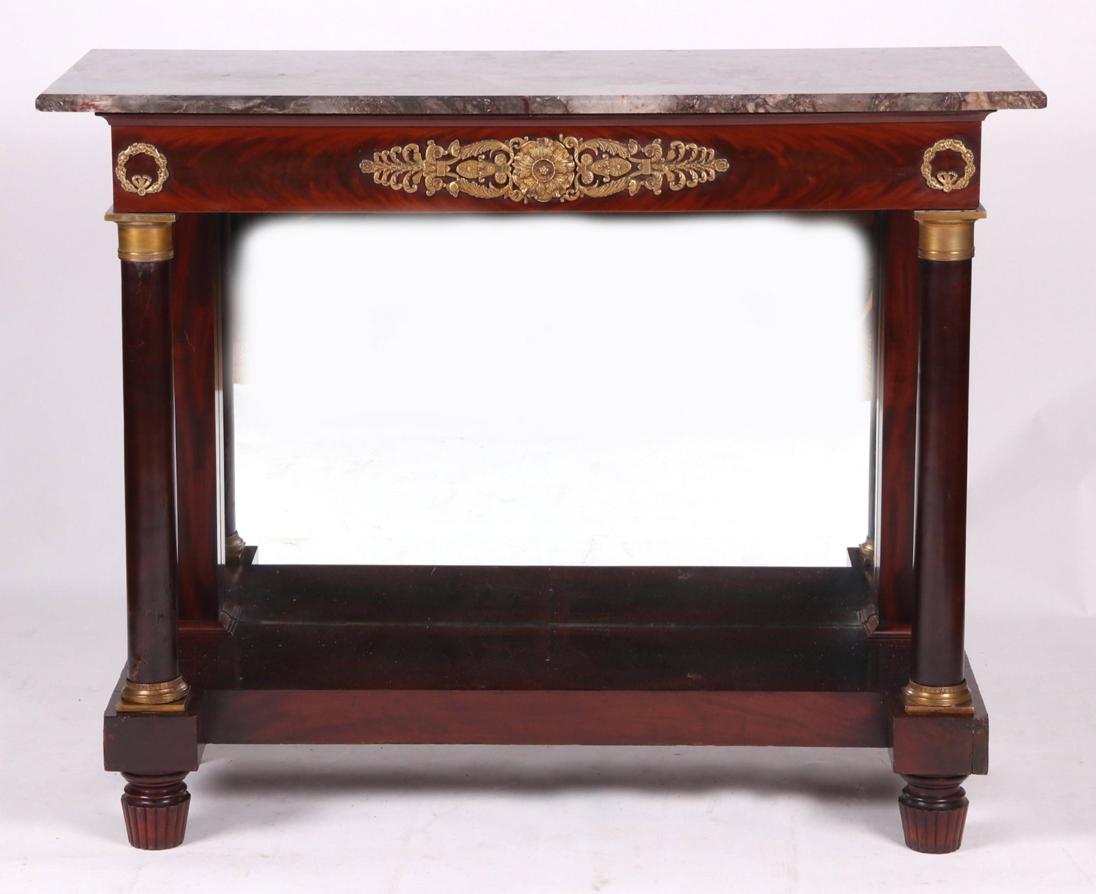A French Mahogany Pier Table: 19th century, with low reeded feet below a rectangular platform, a mirrored back an ormolu mounted frieze, all below a gray marble top. Dimensions: The top is 19" x 50", the height is 40 1/2". Provena