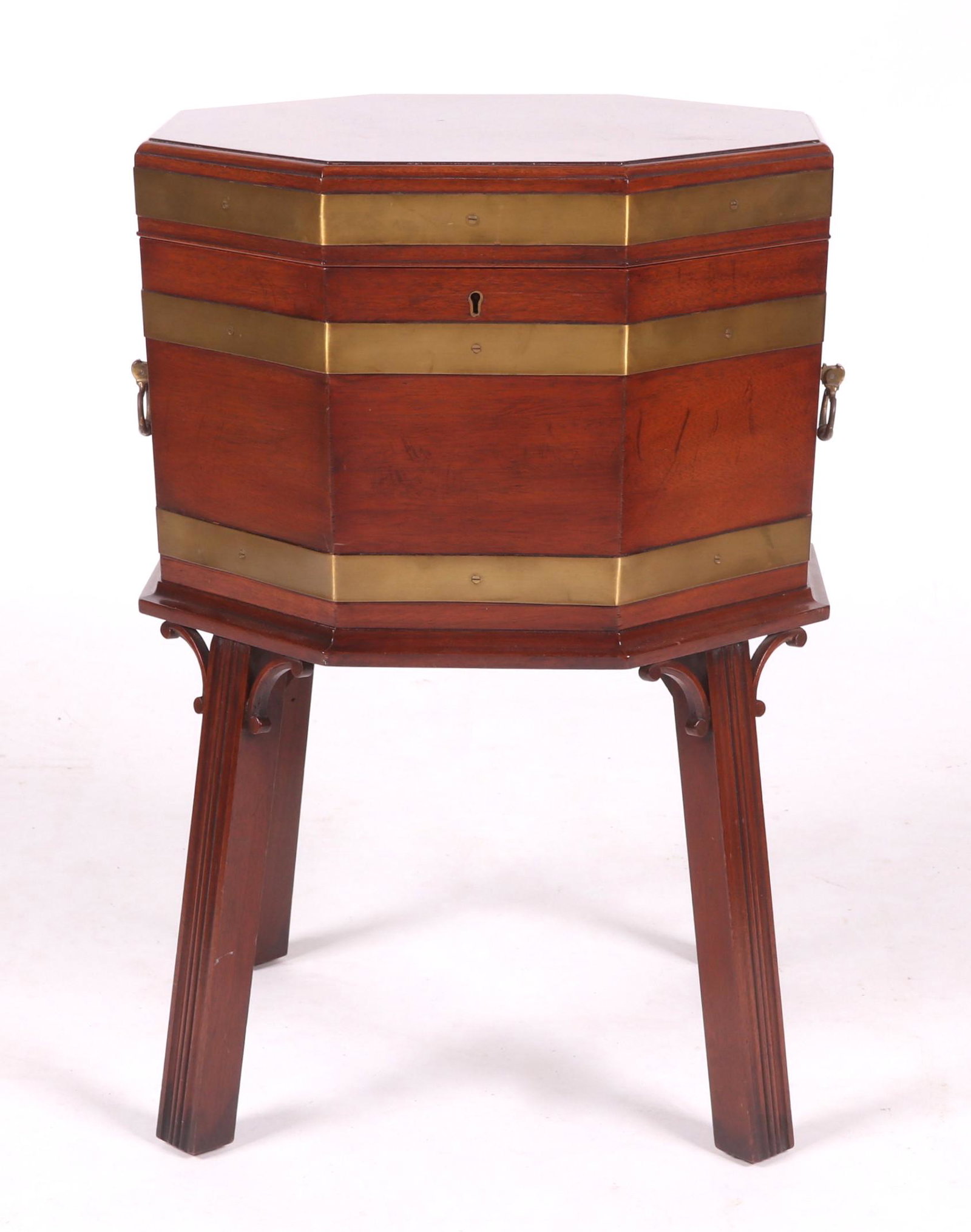A Georgian Style Mahogany Cellarette: 20th century. With canted square legs, C scroll returns below a brass bound octagonal body with hinged lid that opens to reveal a metal liner.The consignor used this piece as an end table. Dimensions: