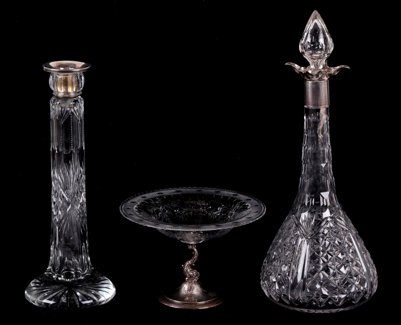 Estate Lot, Cut Crystal and Sterling Items: A compote on a dolphin decorated sterling base marked for Grogan, an early 20th century decanter with a sterling top opening marked for Sheffield, and a heavy cut glass candlestick with a broken sterl