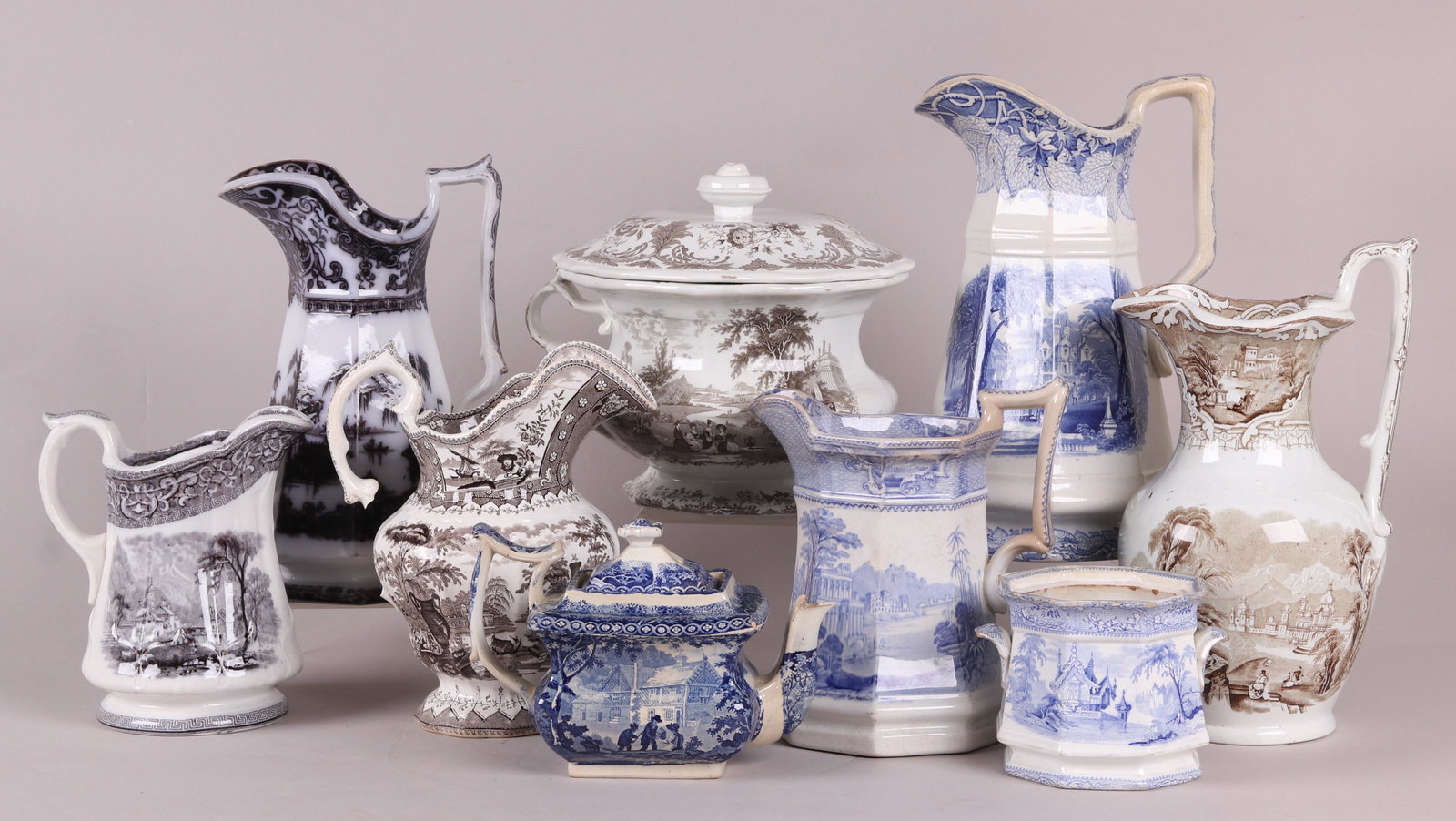 Nine Pieces of 19th Century English Transferware: Comprising: six pitchers in various patterns and colors including an example in the Corean pattern, a chamber pot with lid, a blue sugar bowl (no lid) and a pearlware teapot with blue transfer. Dimens