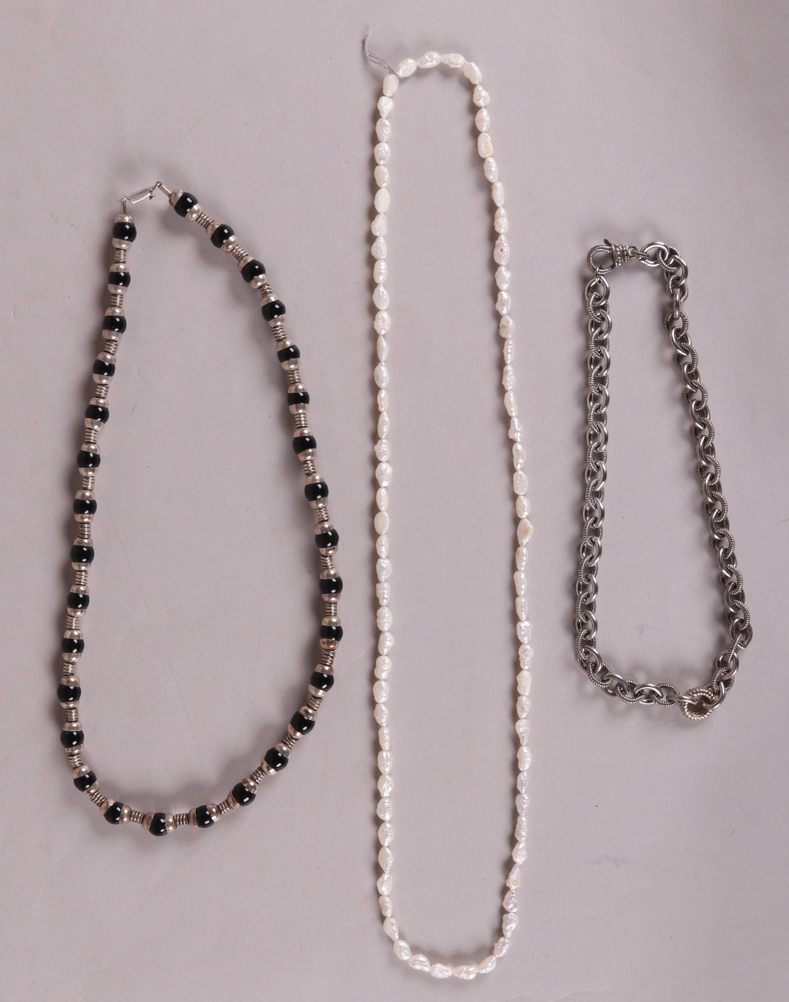 Three Necklaces Including Sterling and Pearls: A Mexican sterling and onyx necklace , a single strand of Biwa pearls and a heavy chain sterling example by Judith Ripka. Dimensions: From from 22" to 31" long. The total approximate gross weight of t