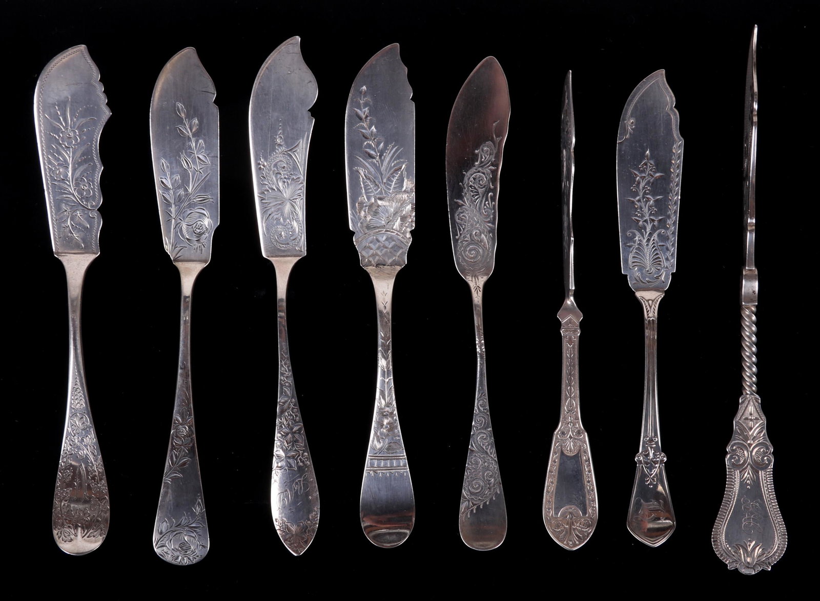 A Group of Silver Master Butter Knives: Coin and sterling silver, each with bright-cut decoration, makers include Gorham, Hutchinson and Connell, C. Heebner, F. L. Archambault, and Whiting. Dimensions: From 7" to 8" long. The total approxim