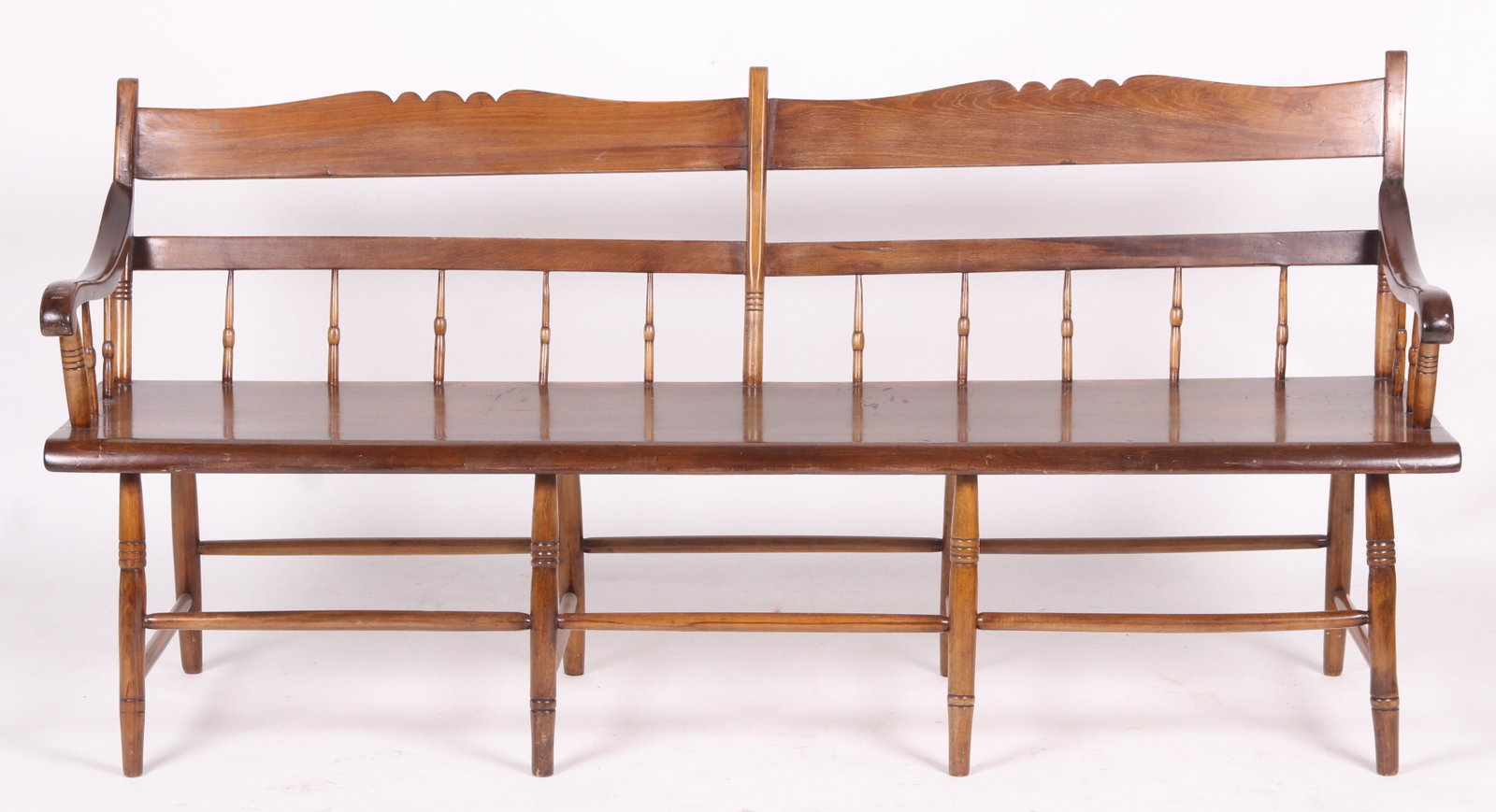 Windsor Half Spindle Settee: 19th century, with ring turned legs, plank seat, scrolled arms and a scalloped crest. Dimensions: 70" x 19", the seat height is 17 1/2", the overall height is 33 1/2". Provenance: From a local collect