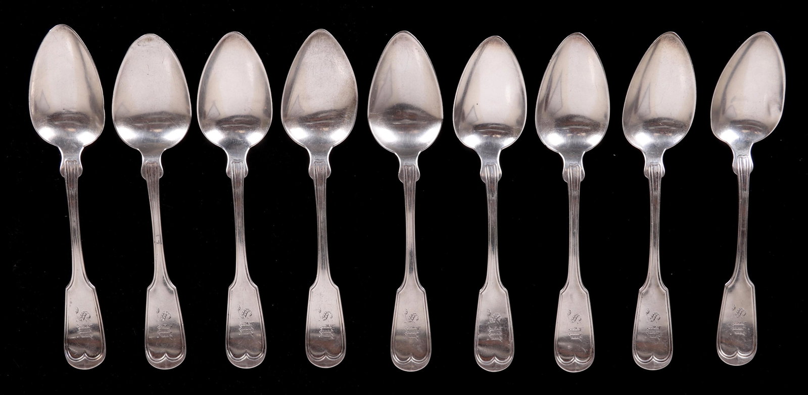 A Set of Coin Silver Spoons Circa 1850: A set of nine dessert spoons marked for William Wilson White and Son, NY. In a fiddle thread pattern. Dimensions: Each is 7 1/4" long, the total approximate weight is 10.2 troy ounces.