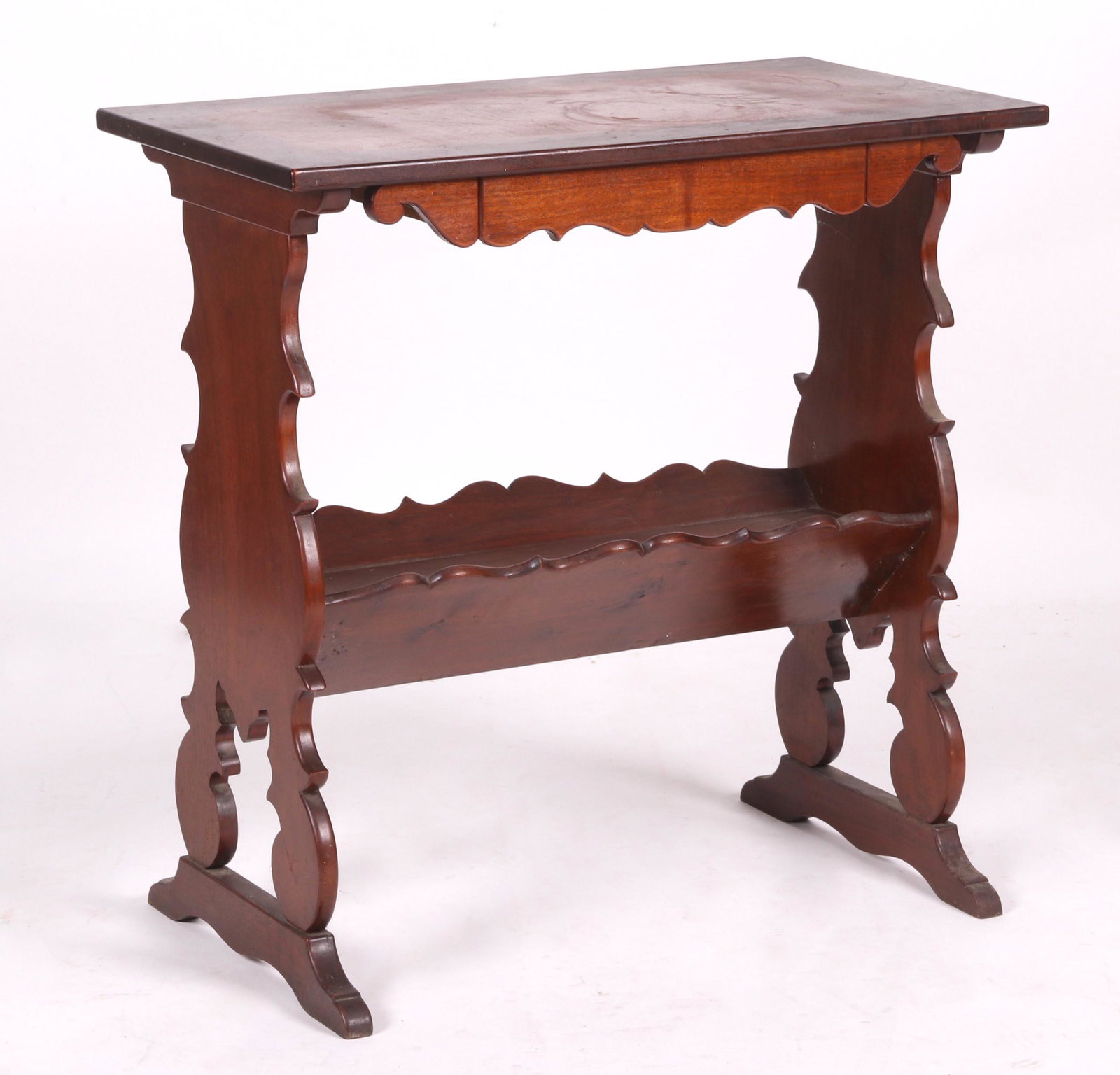 A Walnut Side Table: 20th century, with a deeply scalloped trestle base, low shelf, single drawer and rectangular top. Dimensions: 16" x 30", the height is 30".