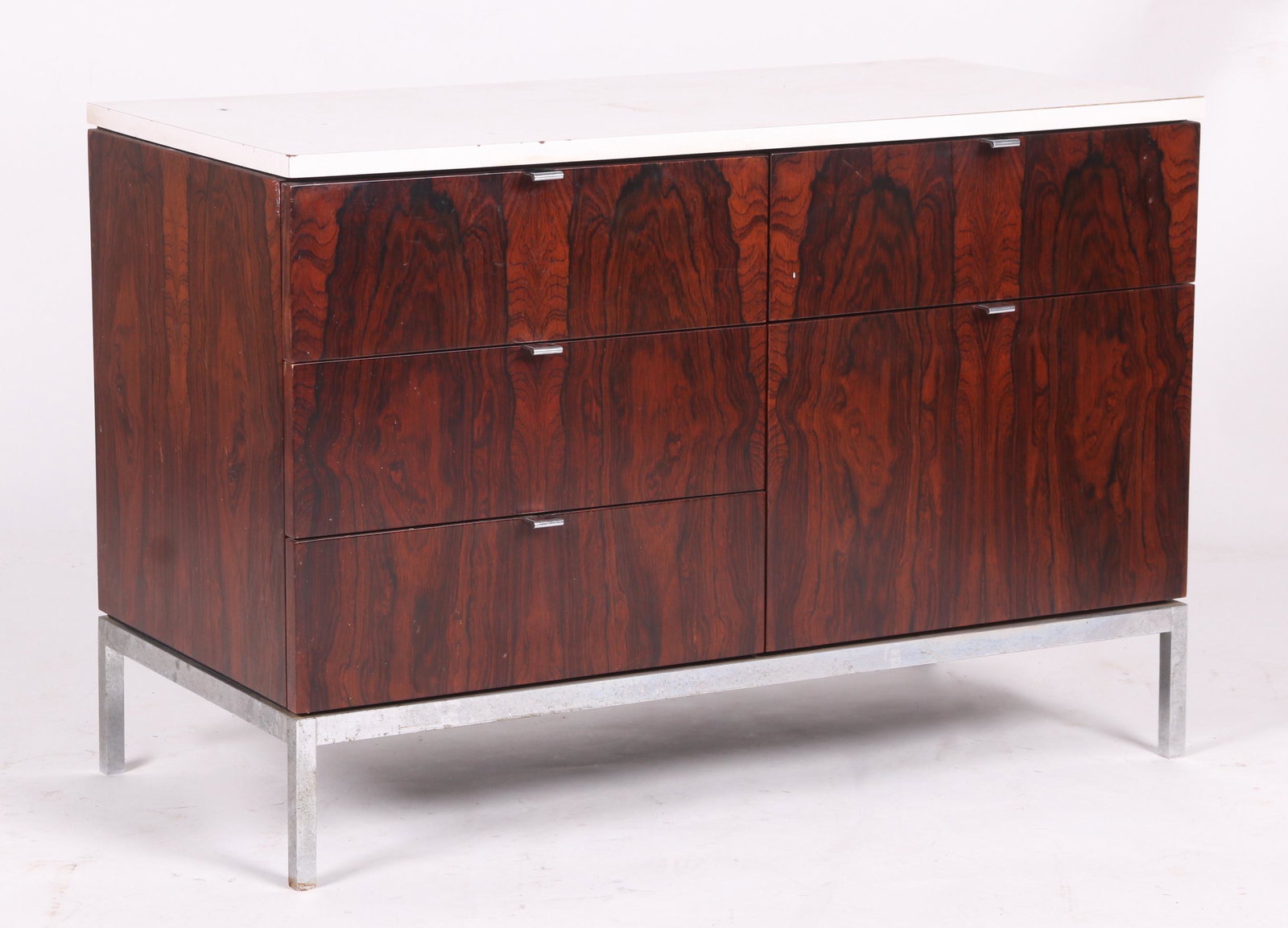 A Five Drawer Credenza by Knoll: A Florence Knoll "lock on top" cabinet with a chrome base, rosewood veneer and a white veneered wooden top. Dimensions: 17 3/4" x 37 1/4", the height is 25 1/2".