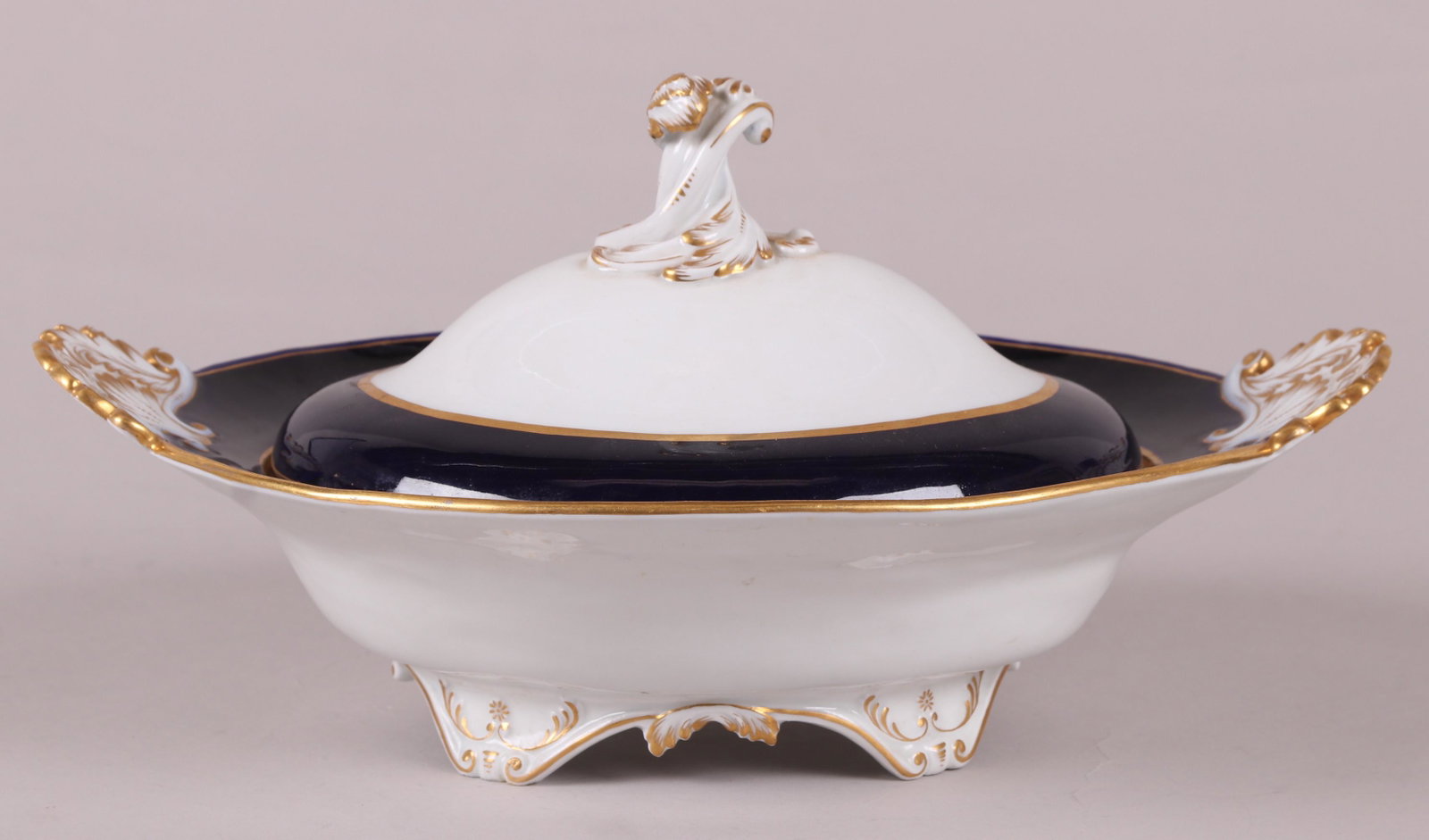 A Meissen Porcelain Covered Server: 19th century, cobalt blue with gilt elements and foliate handles, crossed swords underglaze blue mark as pictured. Dimensions: 13" x 10 3/4", the height is 7". Provenance: From a Bucks County Collecti