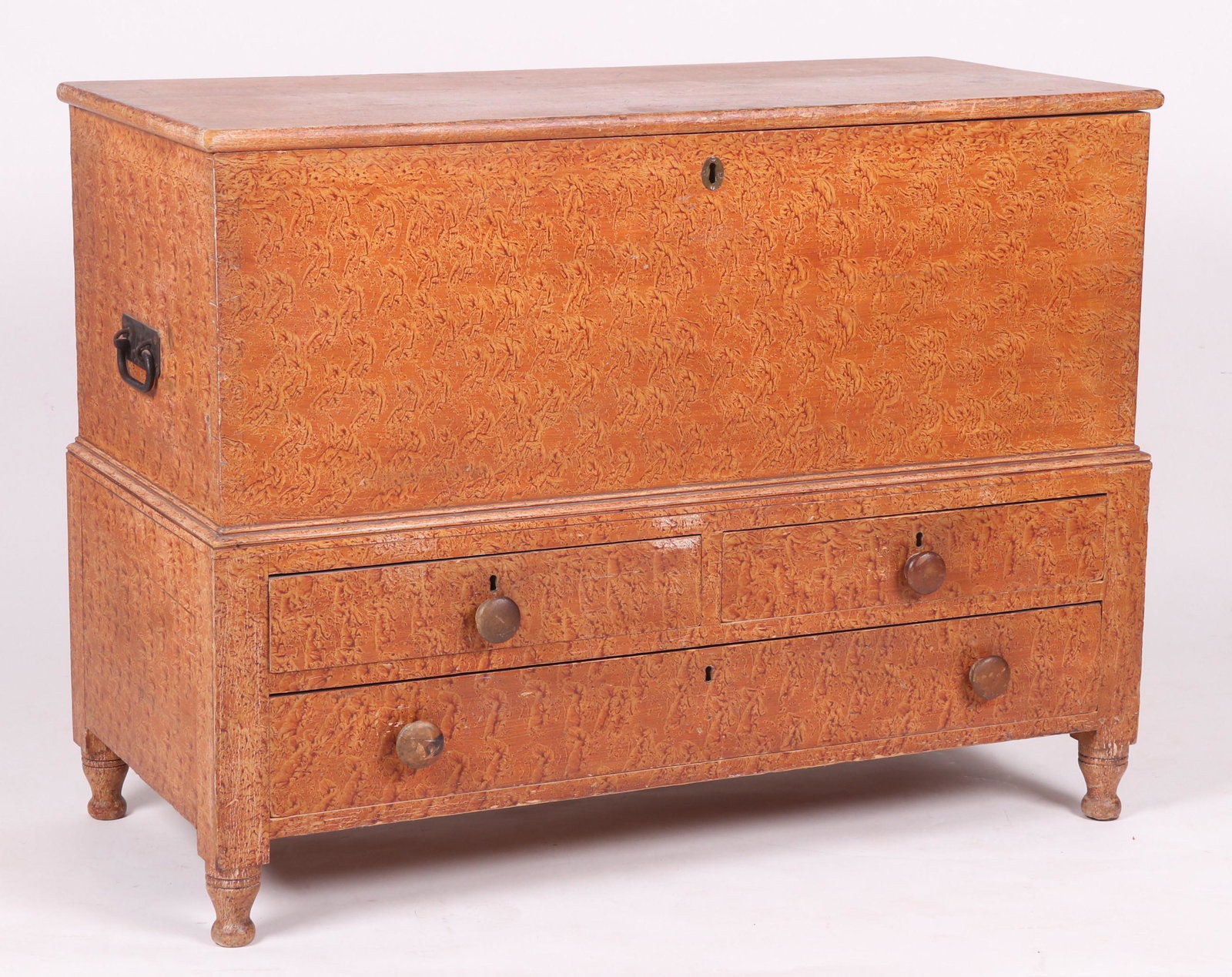 A Paint Decorated Blanket Chest with Drawers: 19th century, with turned feet, a configuration of three drawers, an upper section with a hinged lid and an interior with till. The case is dovetailed and the surface is painted with sponge decoration