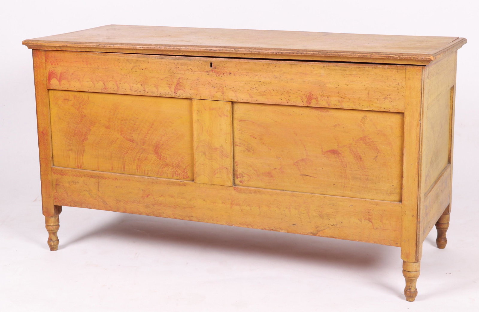A Paint Decorated Paneled Blanket Chest: 19th century, pine, with turned feet, paneled front and sides and yellow paint with red decoration. Dimensions: 49 1/2" x 21", the height is 27 1/2". Provenance: From a Bucks County Collection.