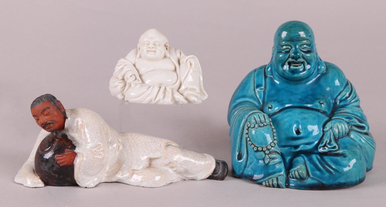 Three Chinese Figures: A blanc de chine Buddha, a Buddha figure with a turquoise glaze and a Shiwan pottery figure of a reclining man. Dimensions: From 5" x 4" to 9 1/2" x 3", the heights range from 3" to 6 1/2". Provenance
