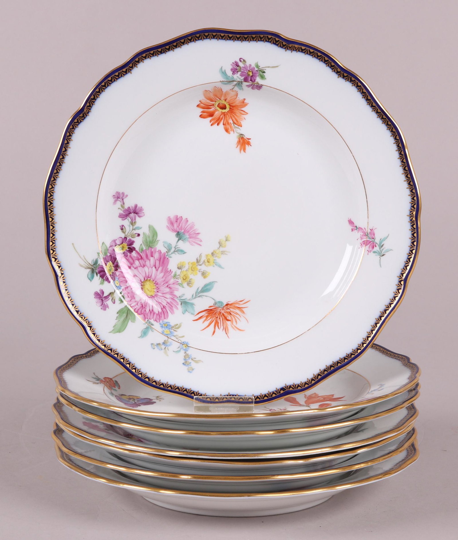 A Set of Meissen Porcelain Deep Plates: Late 19th century, each with a cobalt and gilt border and hand painted floral decoration. Seven total. Dimensions: Each is 9 3/4" in diameter. Provenance: From a PA estate.
