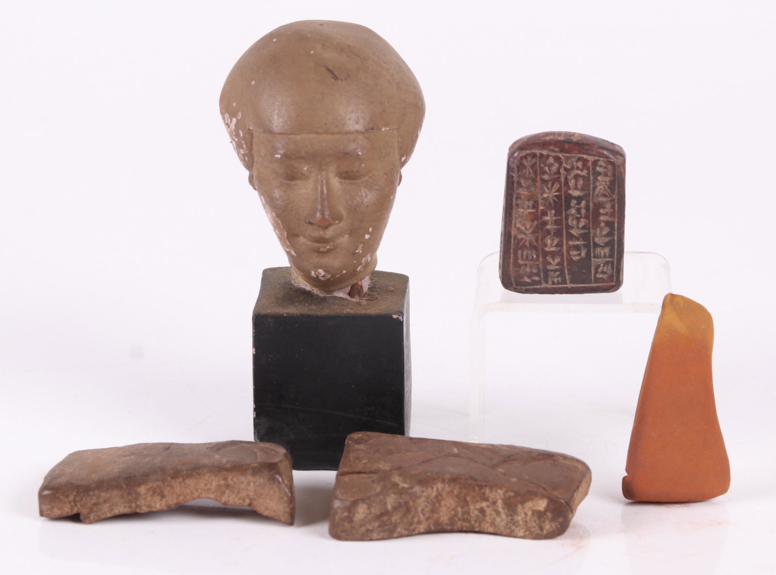 A Group of Ancient Items, Egyptian: A small tablet with hieroglyphs, a small terracotta head, and a stone cosmetics container. Dimensions: From 1 1/4" x 1/2" x 1 3/4" to 2" x3" x 5". Provenance: From a PA estate.