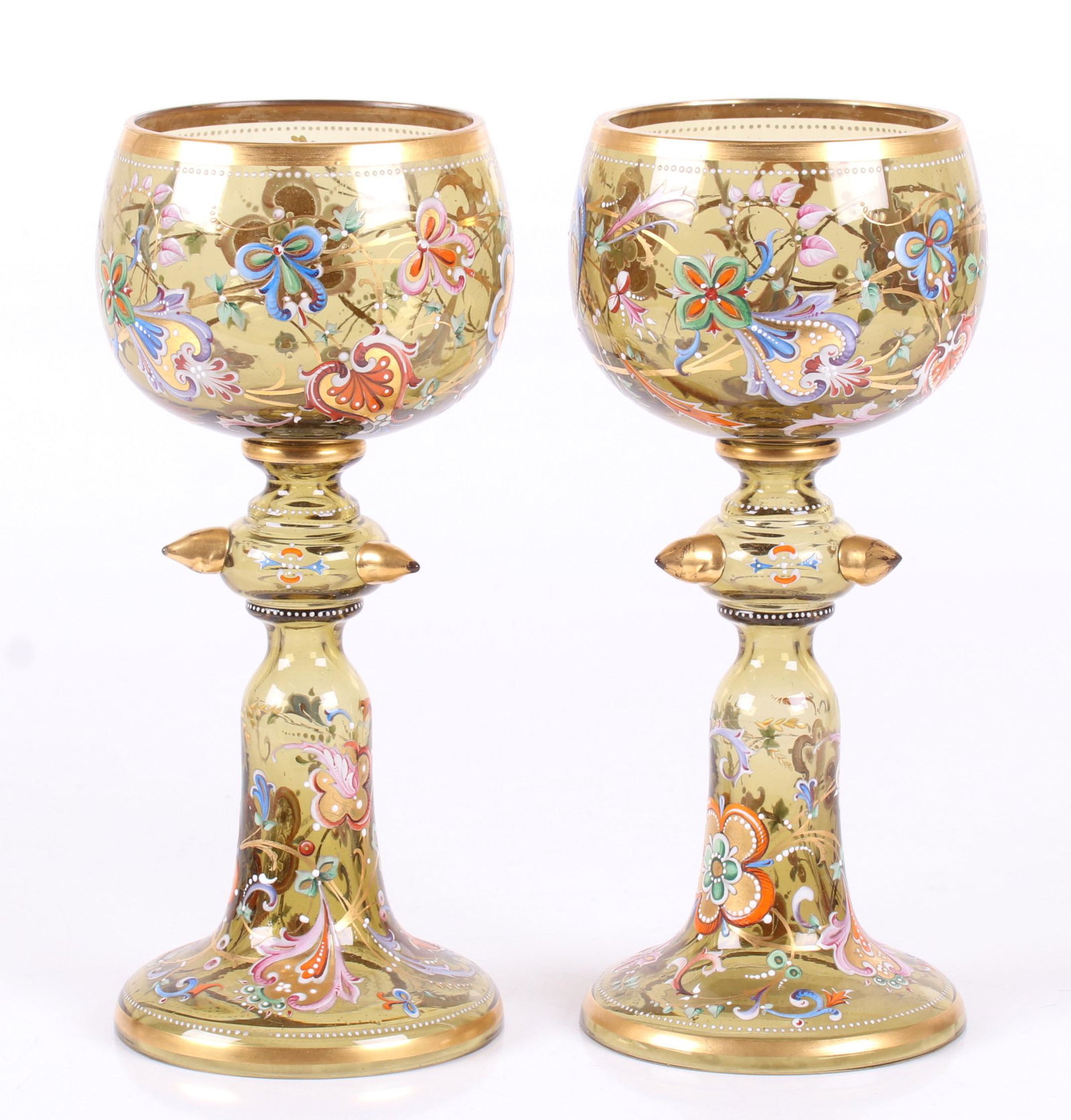A Pair of Bohemian Glass Goblets: Late 19th century, each amber-green, with gilt prunts and good enameled floral decoration. Dimensions: Each is 4 1/2" in diameter, the height is 10". Provenance: From a PA estate.