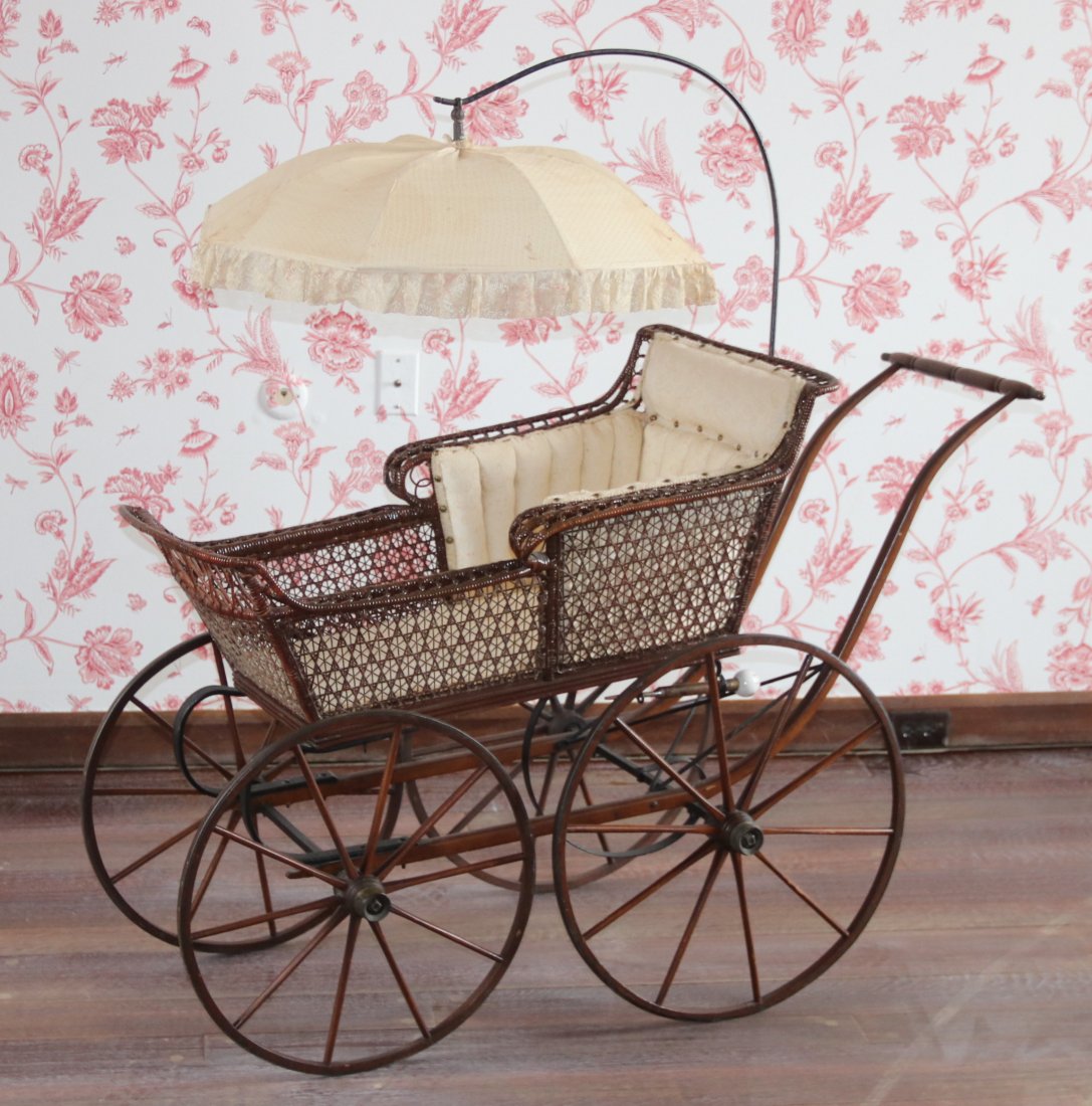 A Victorian Wicker Baby Carriage: Late 19th century, with spoked wooden wheels and attached parasol. Dimensions: 54" x 21" , 52" tall. Provenance: From a local collection.