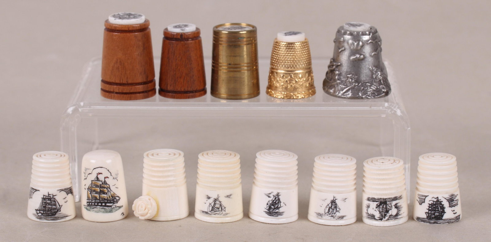 A Group of Scrimshaw Thimbles: Thirteen examples, bone, wood, pewter and gold tone metal. All 20th century. Dimensions: From 3/4" to 1 1/8" tall. Provenance: From a local estate.