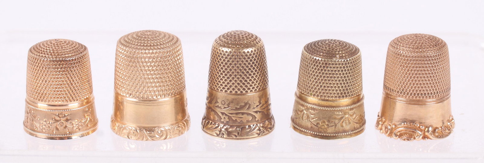 A Group of Five 14k Gold Thimbles: Each with floral or foliate decoration, late 19th or early 20th century. All tested as 14k yellow gold. One retains the leather box. Dimensions: The total approximate weight is 10.9dwt. Provenance: Fr